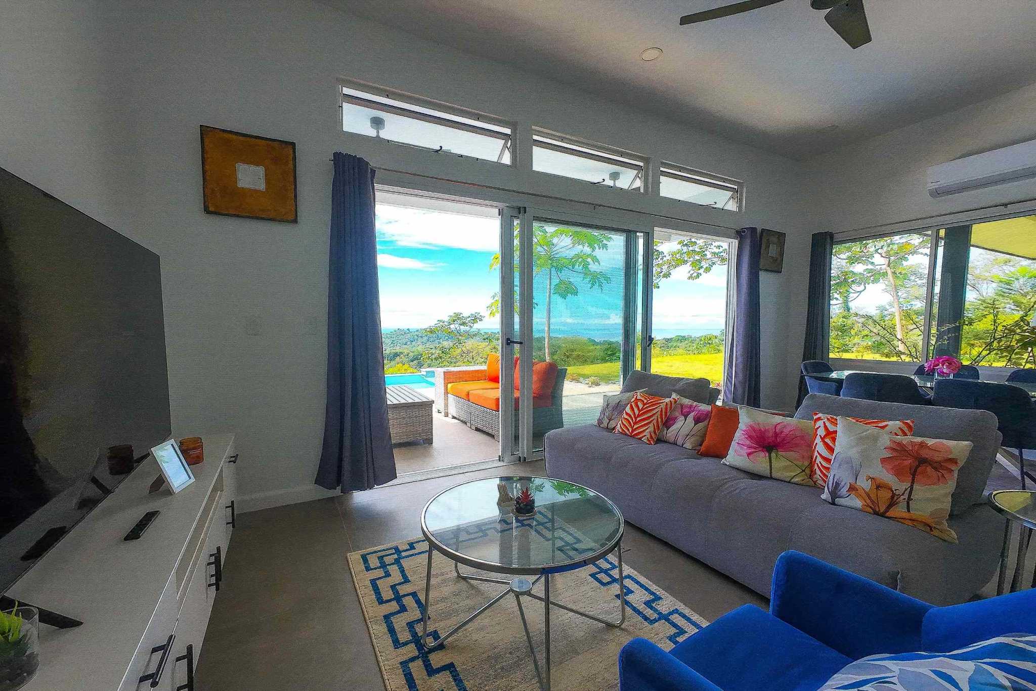 Mountain & Ocean View Home living room with sofa and glass doors to terrace with mountain views in Ojochal, Costa Rica