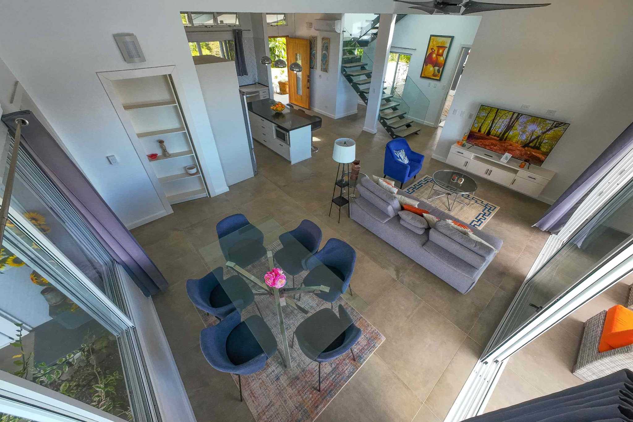Mountain & Ocean View Retreat living and dining area with blue chairs, gray sofa and kitchen island in Ojochal, Costa Rica