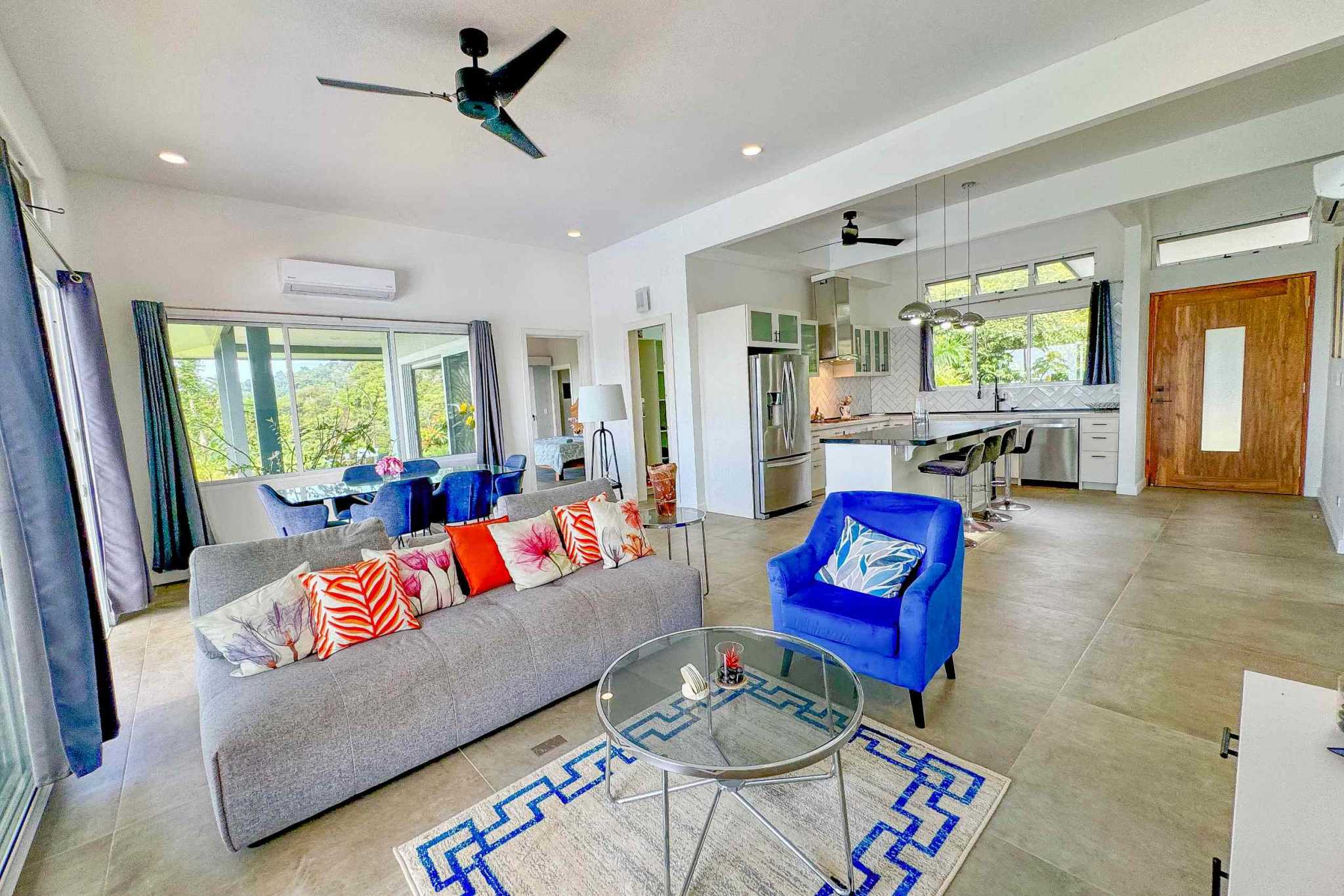 Mountain & Ocean View Retreat open living room and kitchen with colorful decor and large windows in Ojochal, Costa Rica