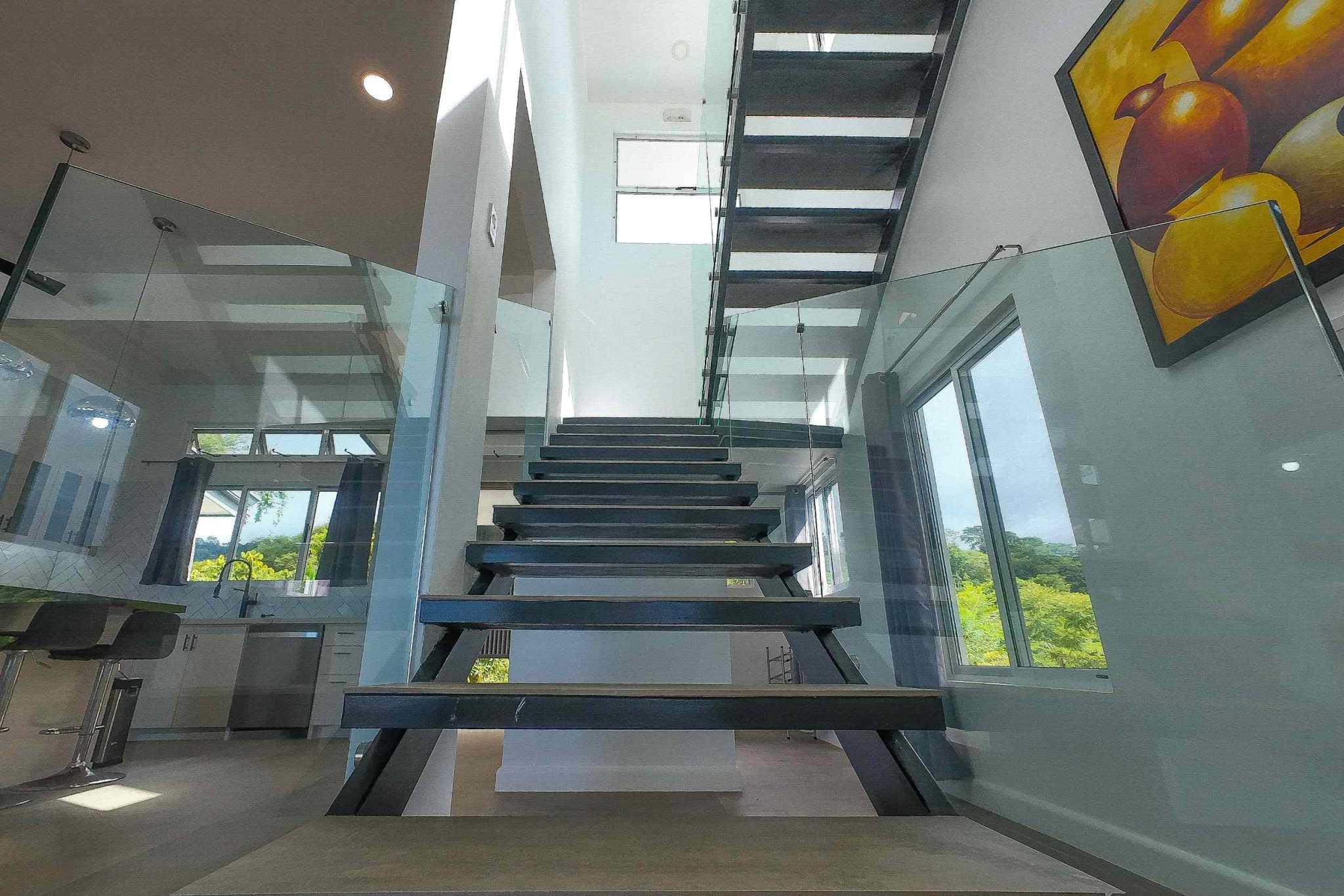 Luxury Mountain Retreat floating steel staircase with glass railings and kitchen view below in Ojochal, Costa Rica
