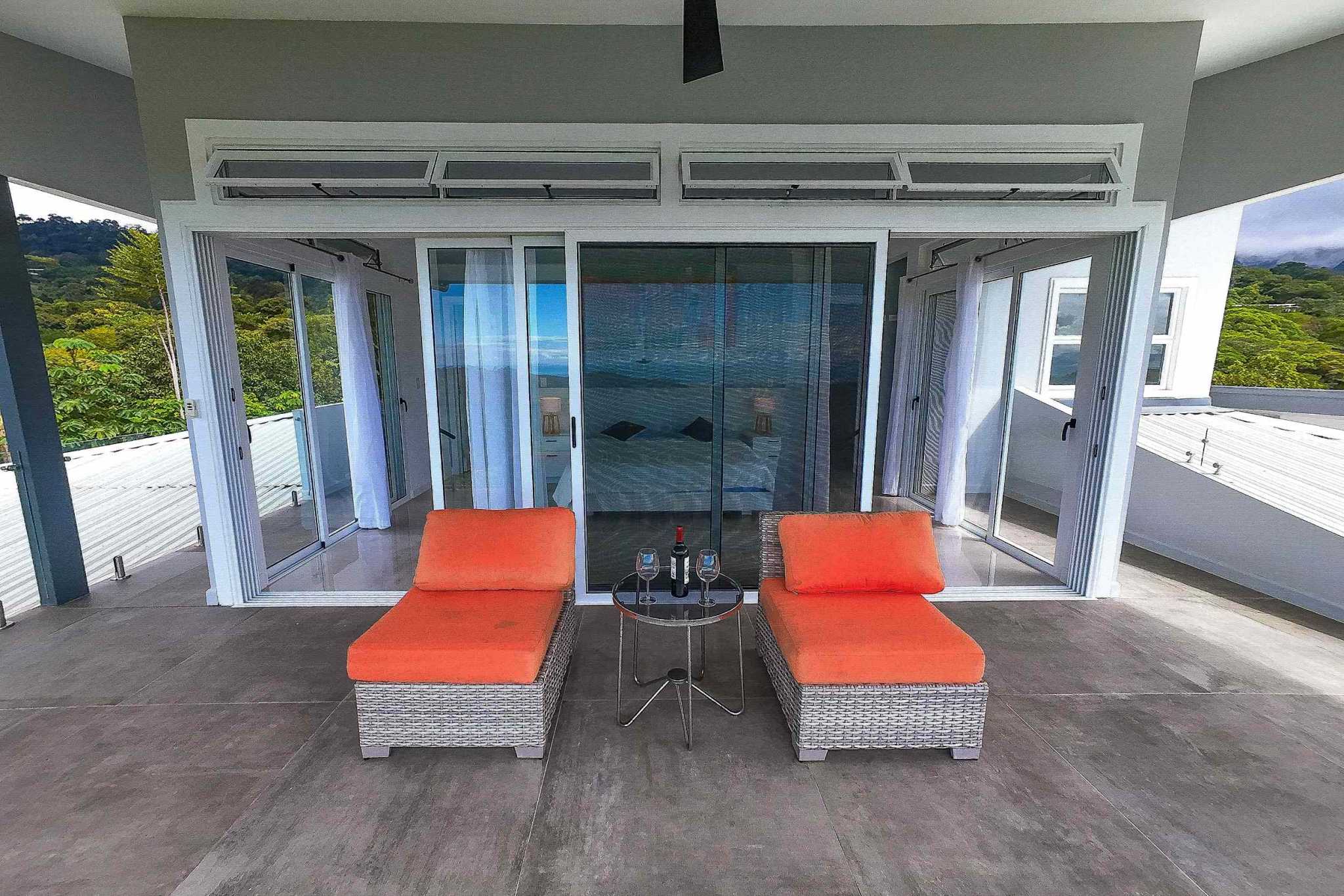 Mountain & Ocean View Retreat covered terrace with orange loungers and wine table in Ojochal, Costa Rica