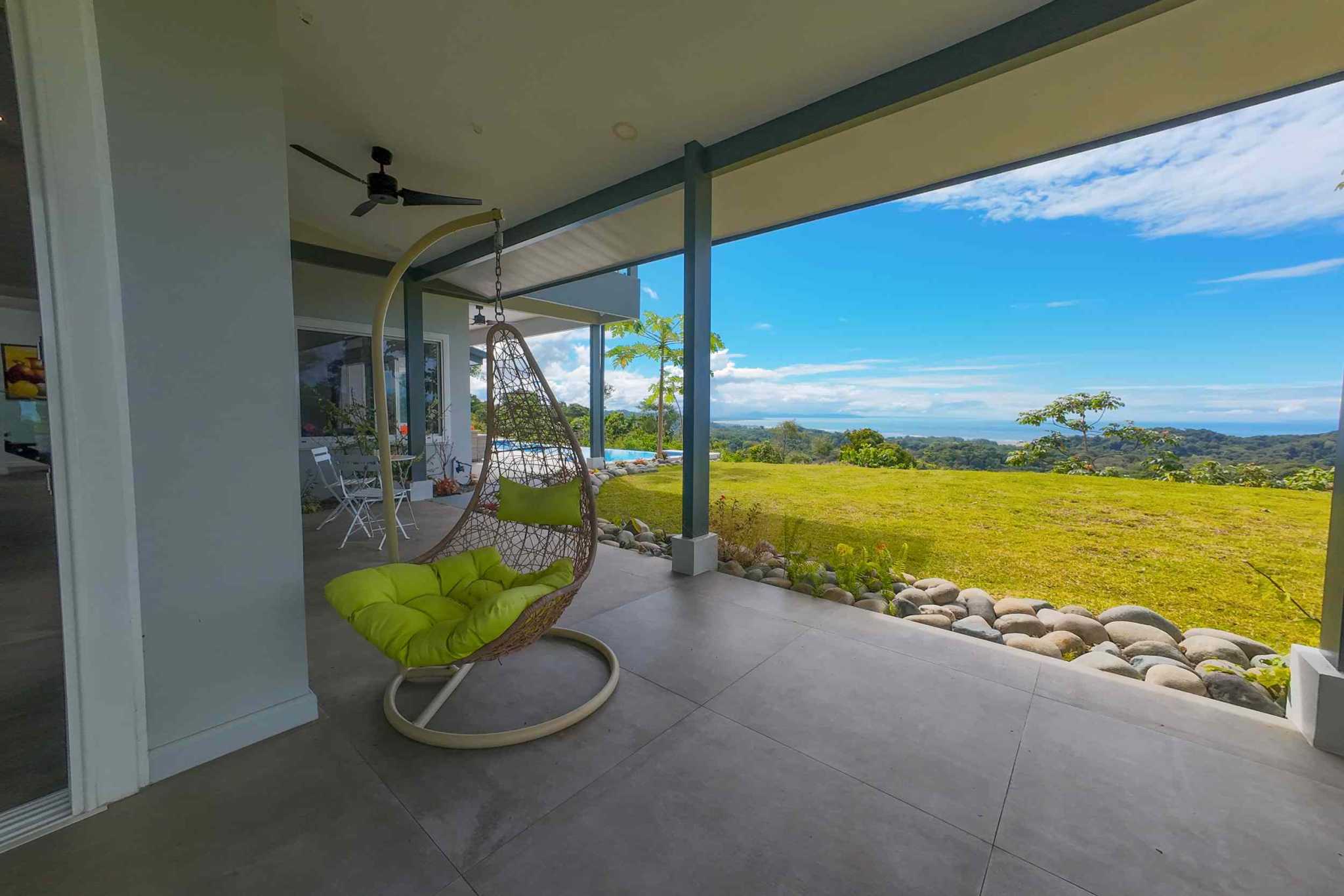 Mountain & Ocean View Retreat covered patio with hanging chair and ocean view in Ojochal, Costa Rica