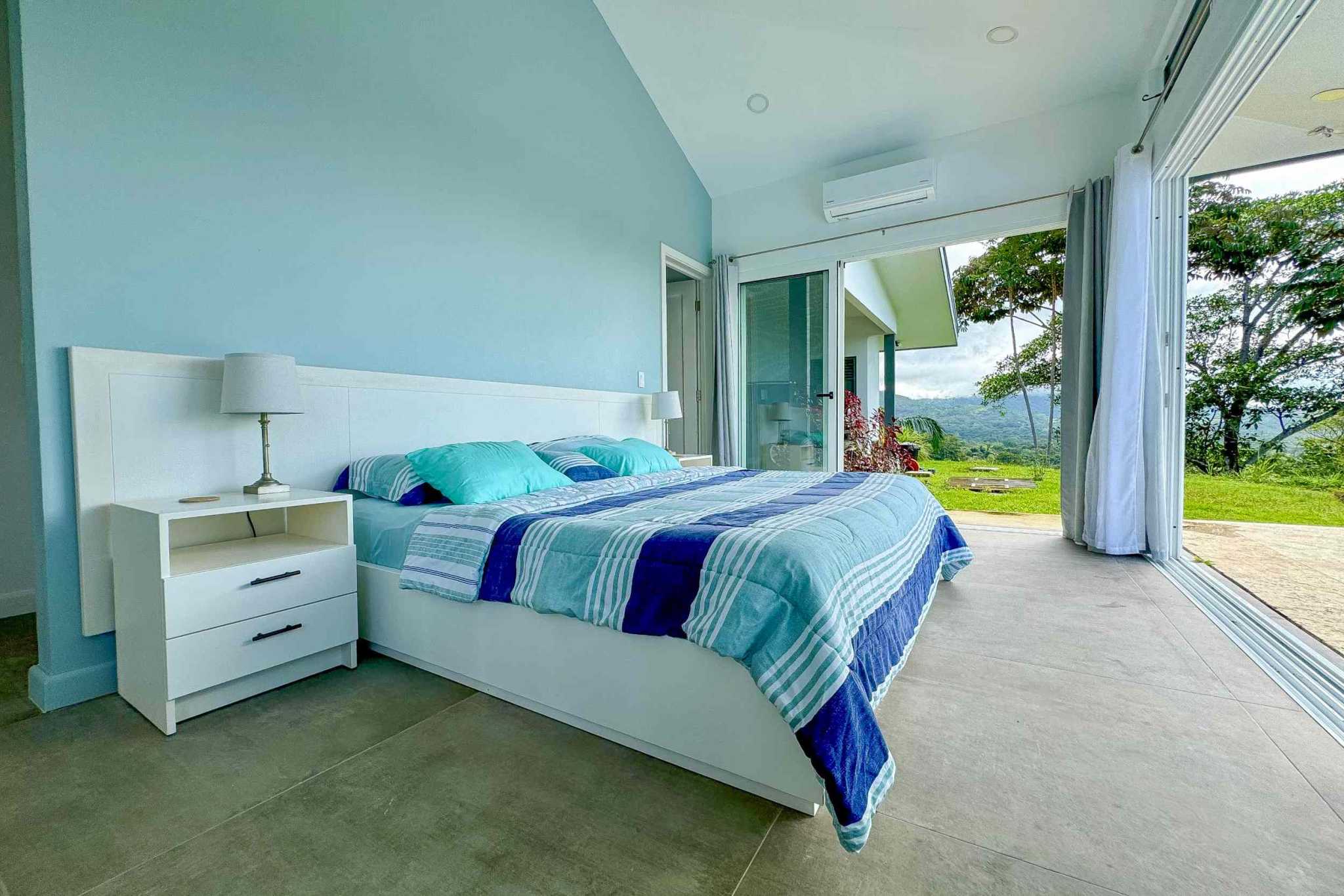 Mountain View Retreat bedroom with king bed and glass doors opening to lush hills in Ojochal, Costa Rica