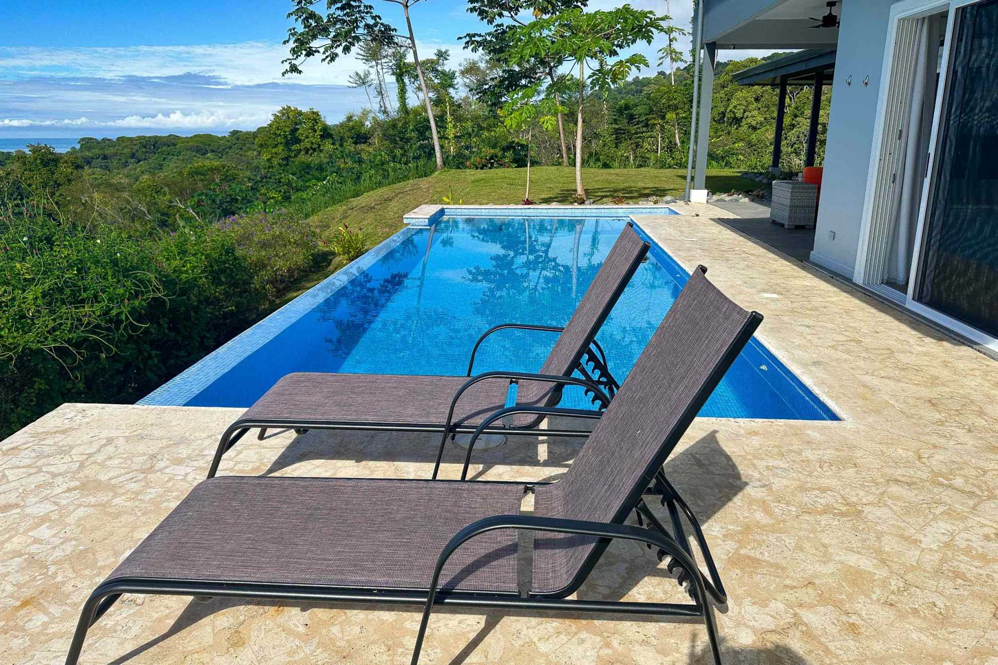 Luxury Mountain Retreat infinity pool with lounge chairs and ocean view in Ojochal, Costa Rica