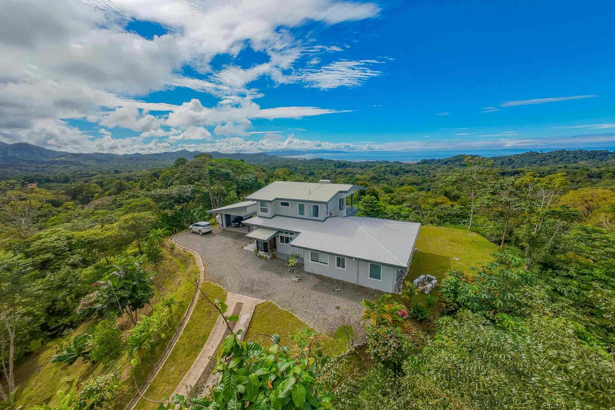 Luxury Retreat aerial view of home with gravel driveway and forest surroundings in Ojochal, Costa Rica