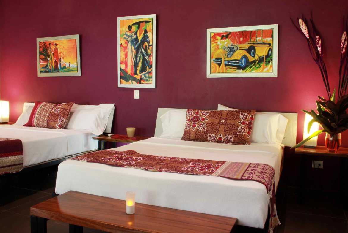 6-Bedroom Business Property guest room with two beds, magenta wall and colorful artwork in Ojochal, Costa Rica