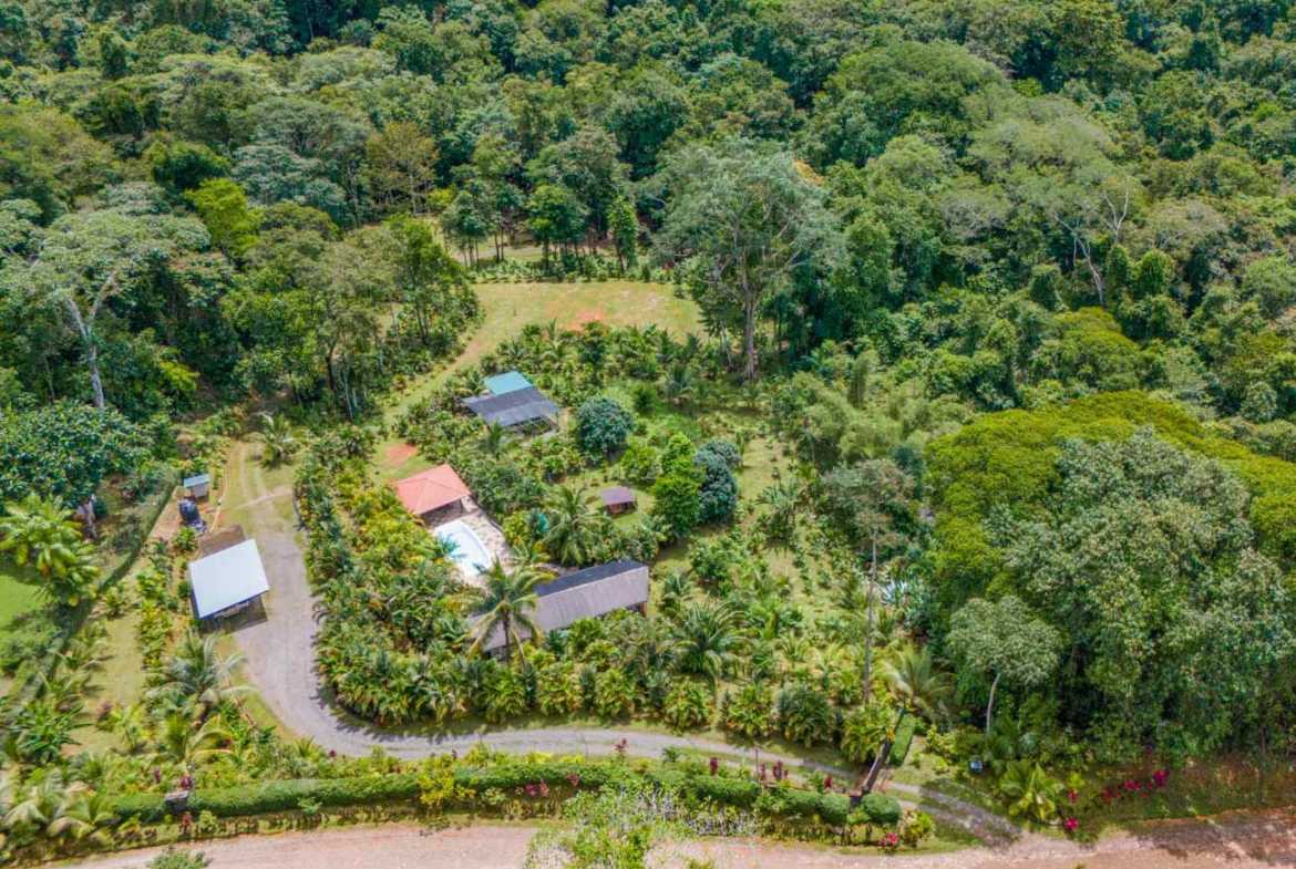 2-Bedroom Home with Pool aerial view of house, pool and outbuildings amid rainforest in Ojochal, Costa Rica