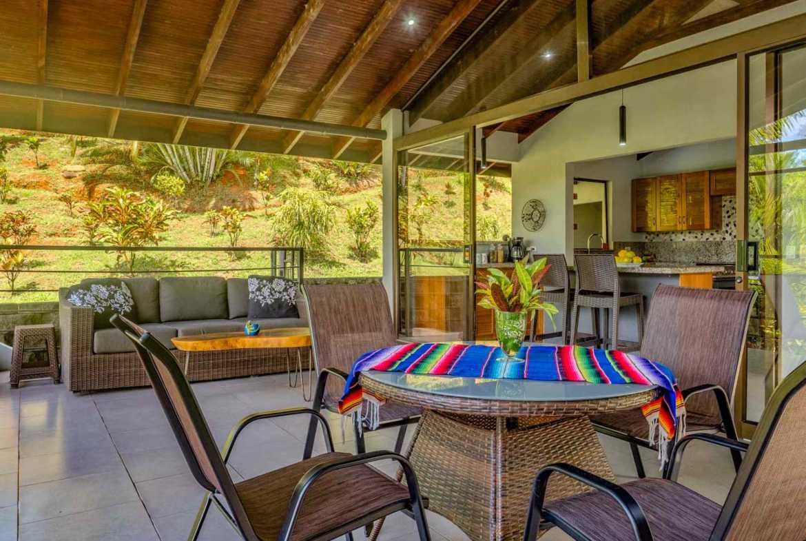 2-Bedroom Home covered patio with dining table and kitchen view in Ojochal, Costa Rica