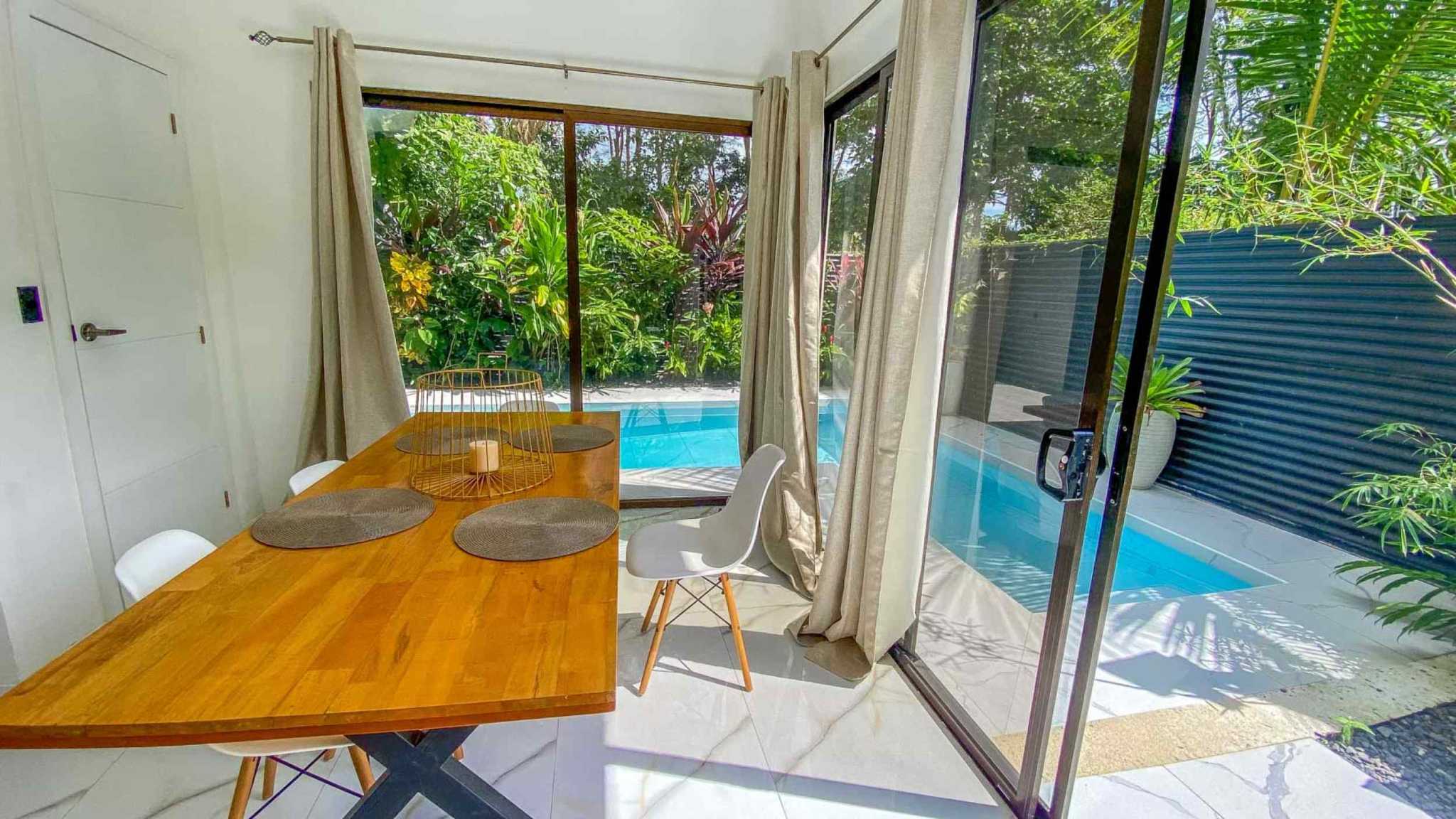 55856-9 3-Bedroom Home with Pool: wood dining table by sliding glass doors opening to a plunge pool and garden in Bahia, Costa Rica