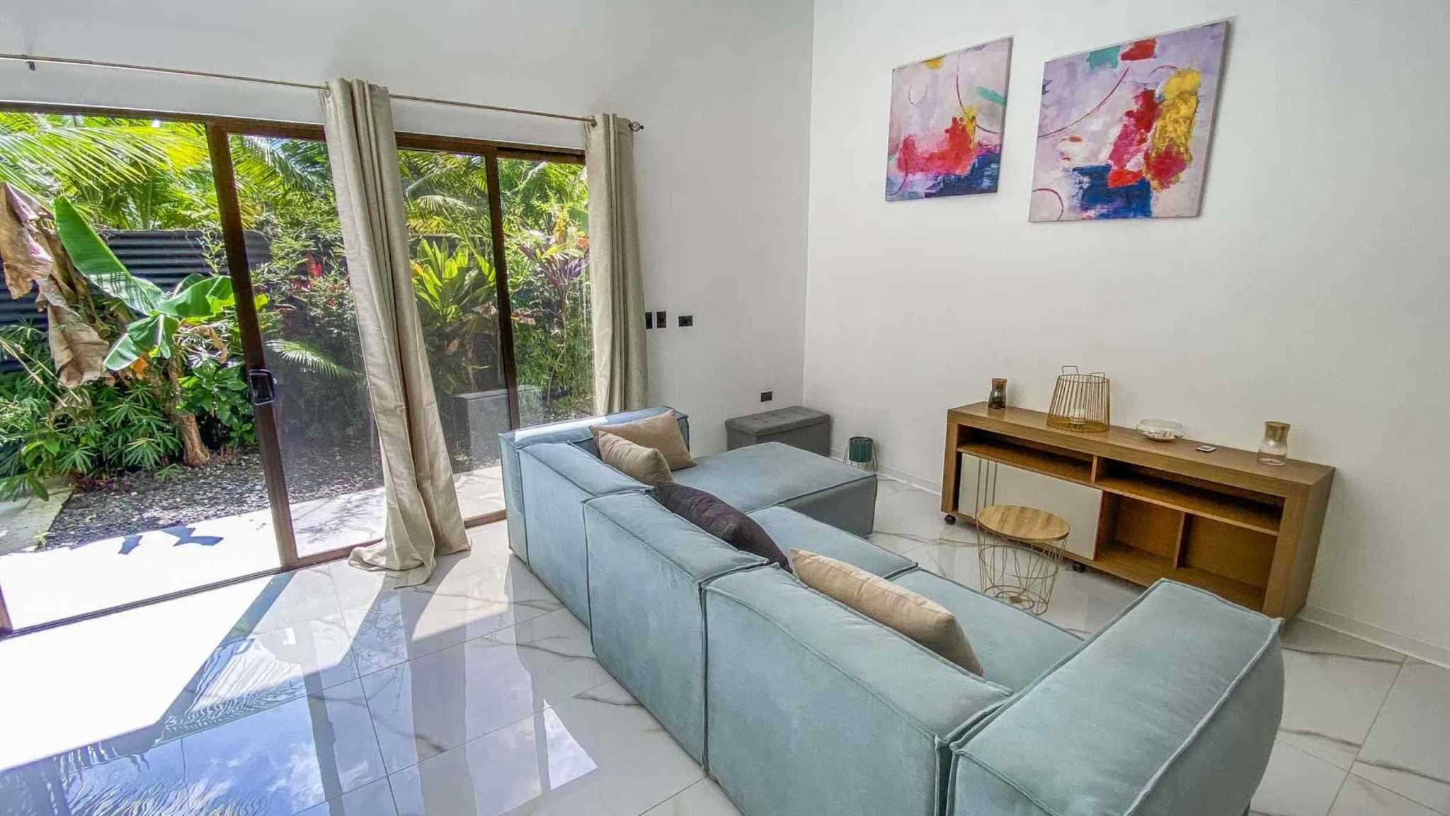 55856-7 3-Bedroom Home with Pool: bright living room, blue sectional, sliding doors to tropical garden in Bahia, Costa Rica