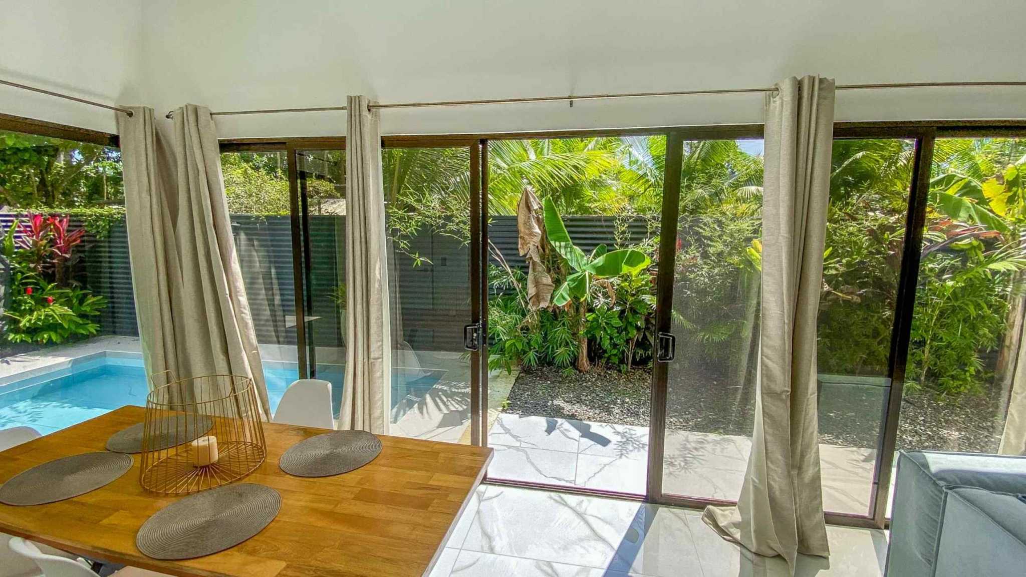 55856-8 3-Bedroom Home with Pool: dining table by sliding glass doors overlooking pool and tropical garden in Bahia, Costa Rica