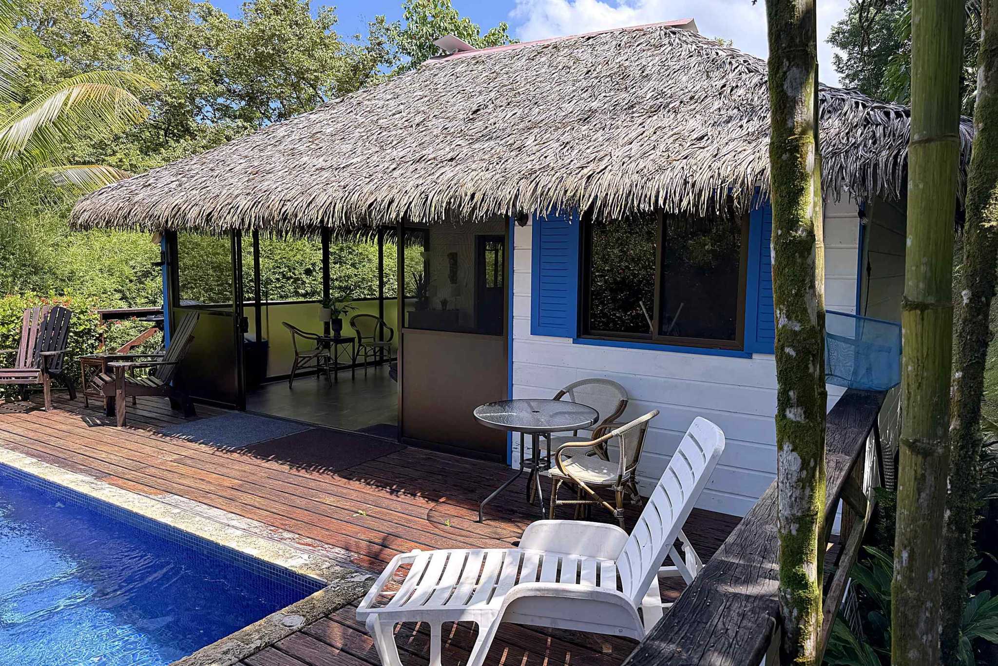 65486-03 Jungle Sanctuary bungalow with thatched roof, pool deck, and lounge chairs in Ojochal, Costa Rica