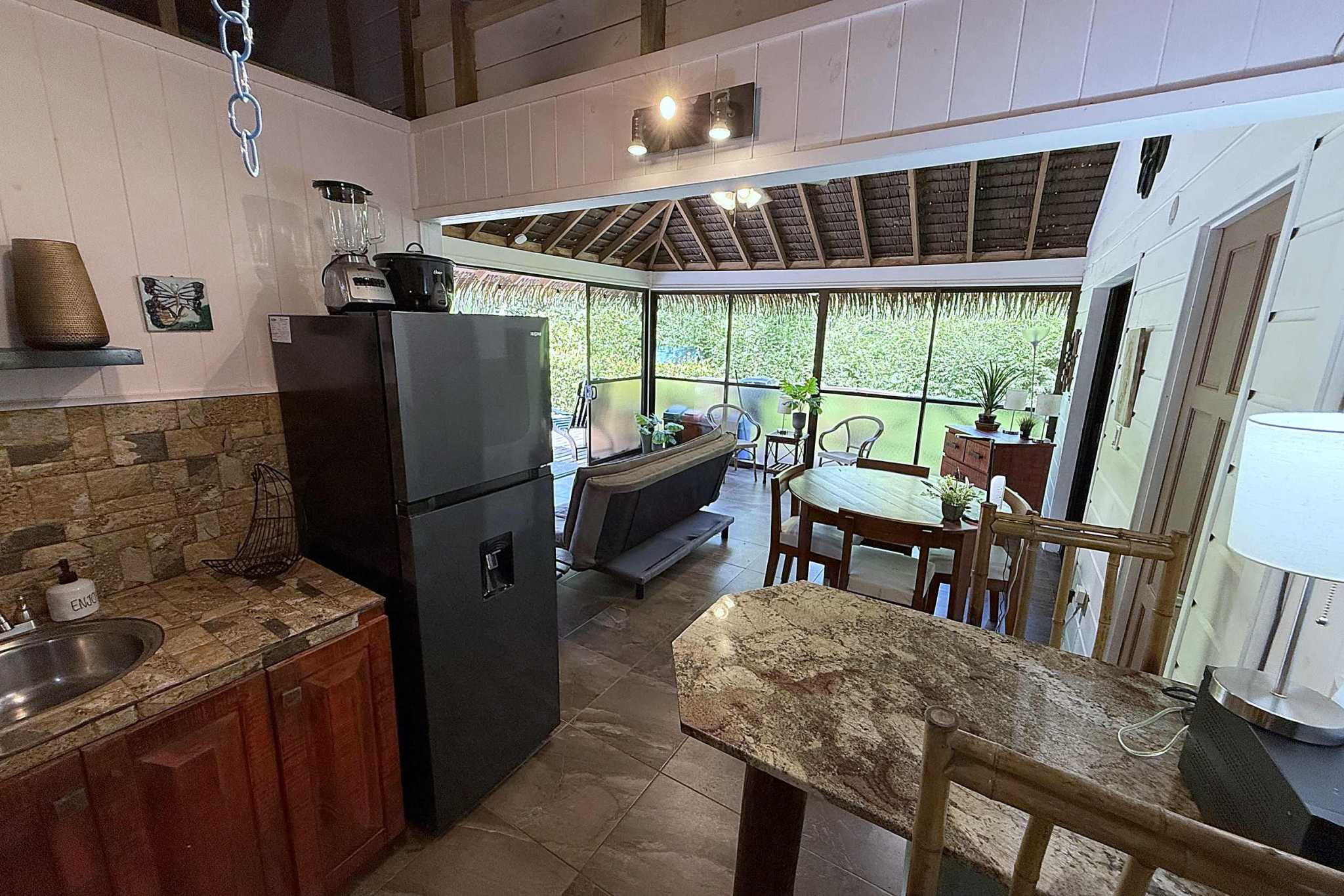65486-10 Jungle Sanctuary kitchen with granite counters opening to screened living and dining area with jungle view in Ojochal, Costa Rica