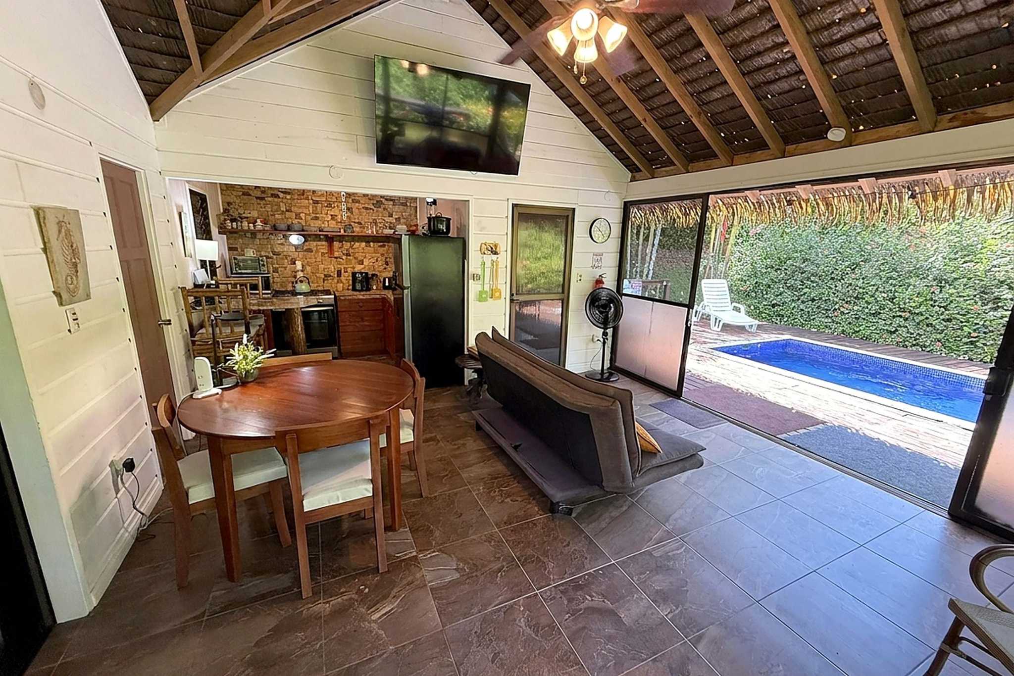 65486-12 Jungle Sanctuary living and dining area with vaulted ceiling and pool view in Ojochal, Costa Rica