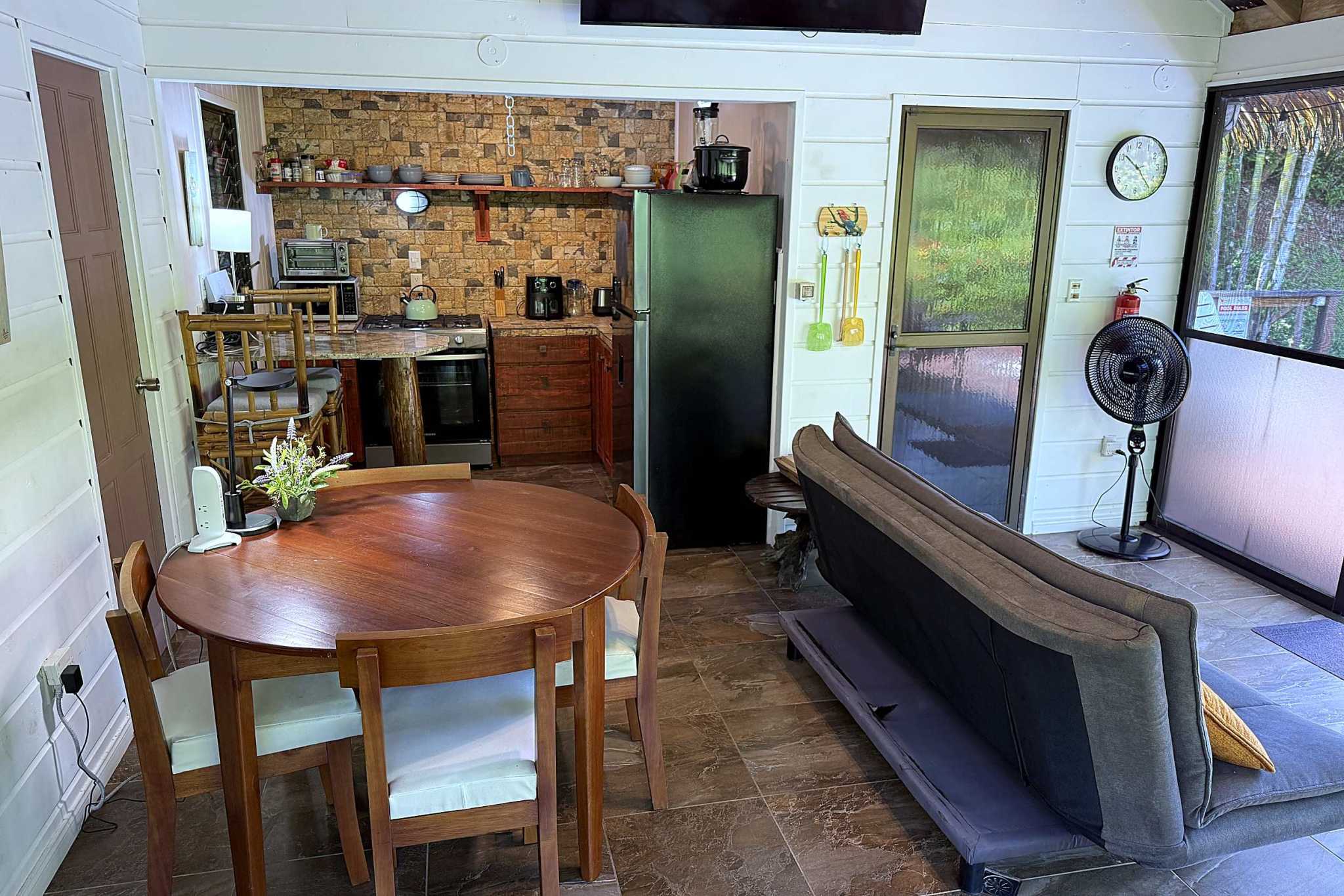 65486-13 Jungle Sanctuary kitchen and dining area with round wooden table and stone backsplash in Ojochal, Costa Rica