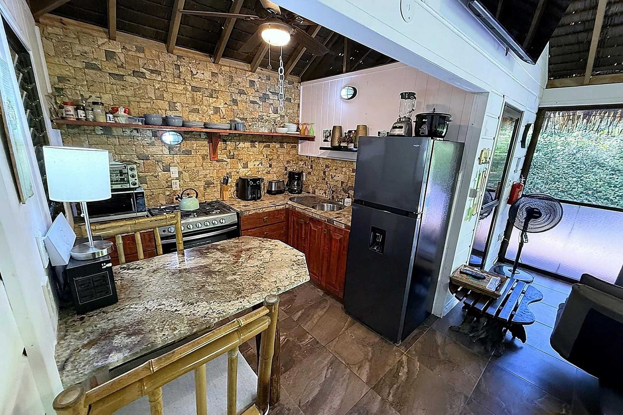65486-14 Jungle Sanctuary Villa kitchen and dining area with stone wall and granite counters in Ojochal, Costa Rica