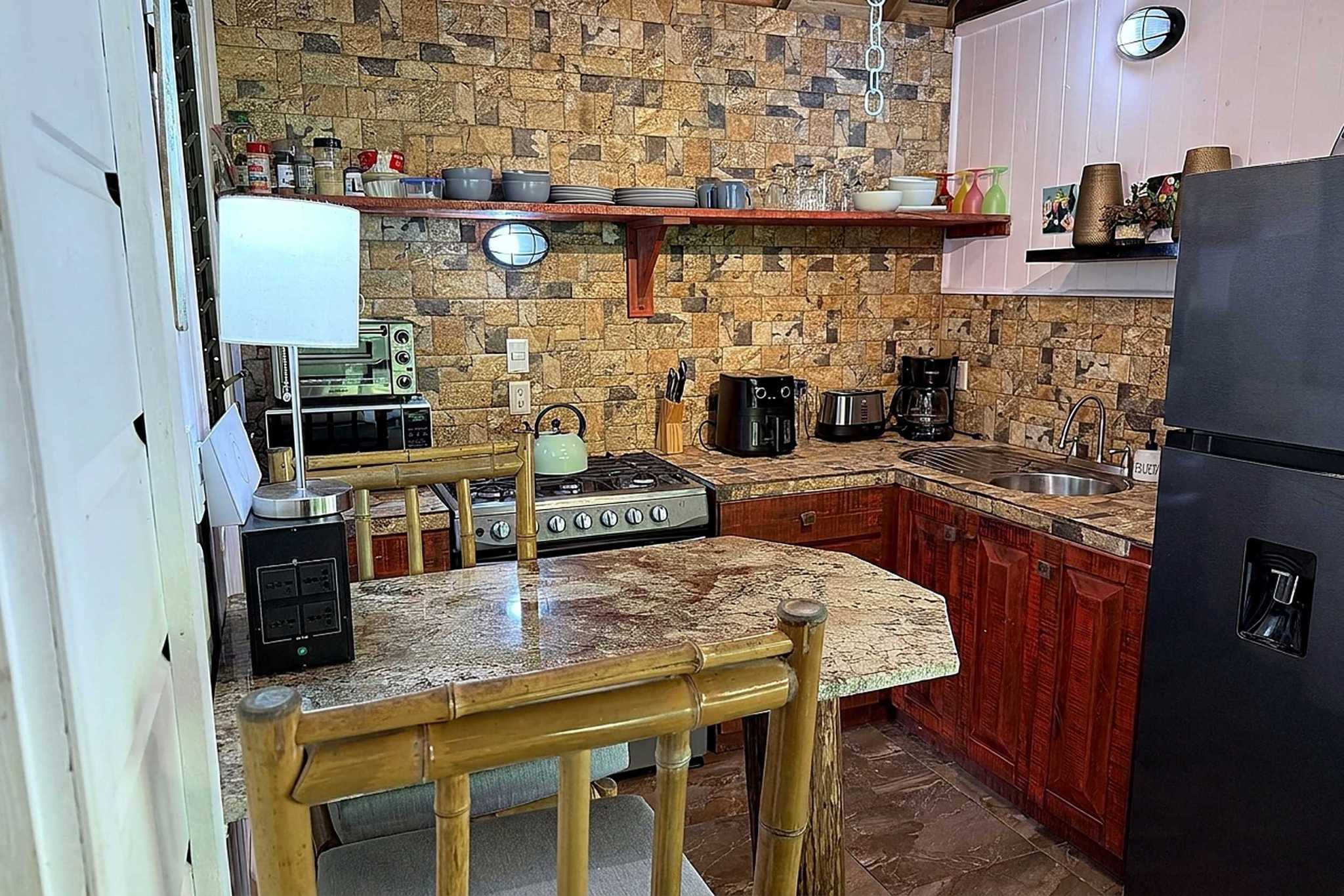 65486-15 Jungle Sanctuary Retreat kitchen with stone backsplash, red cabinets, and bamboo breakfast bar in Ojochal, Costa Rica