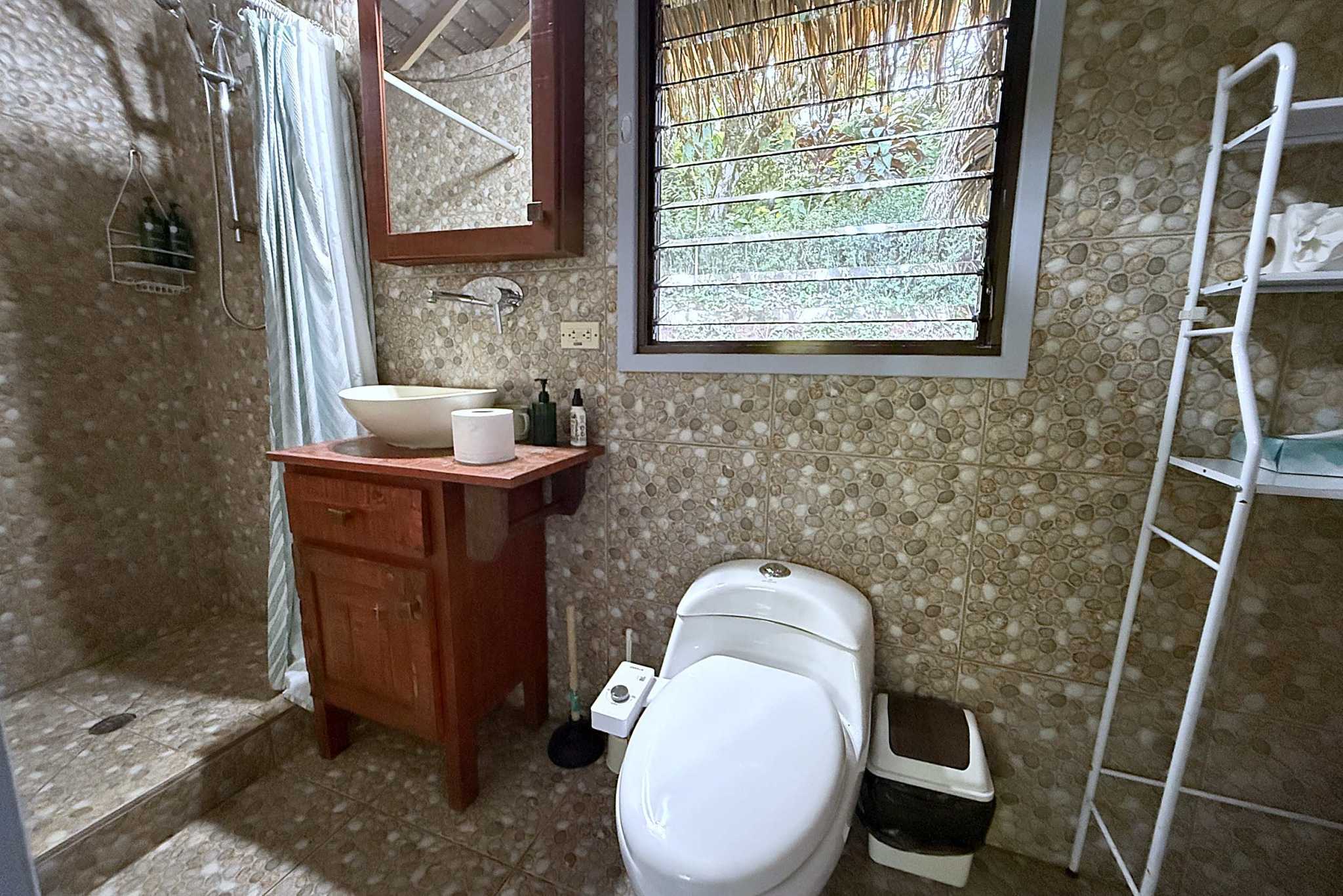 65486-23 Jungle Sanctuary bathroom with pebble tile, vessel sink, and jungle-view window in Ojochal, Costa Rica