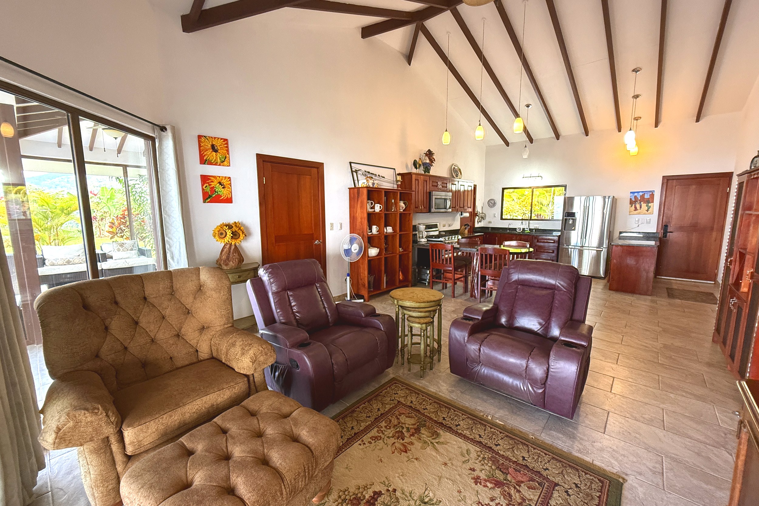 Living room with leather recliners, vaulted ceiling, and glass doors opening to the terrace in Toucan Valley.