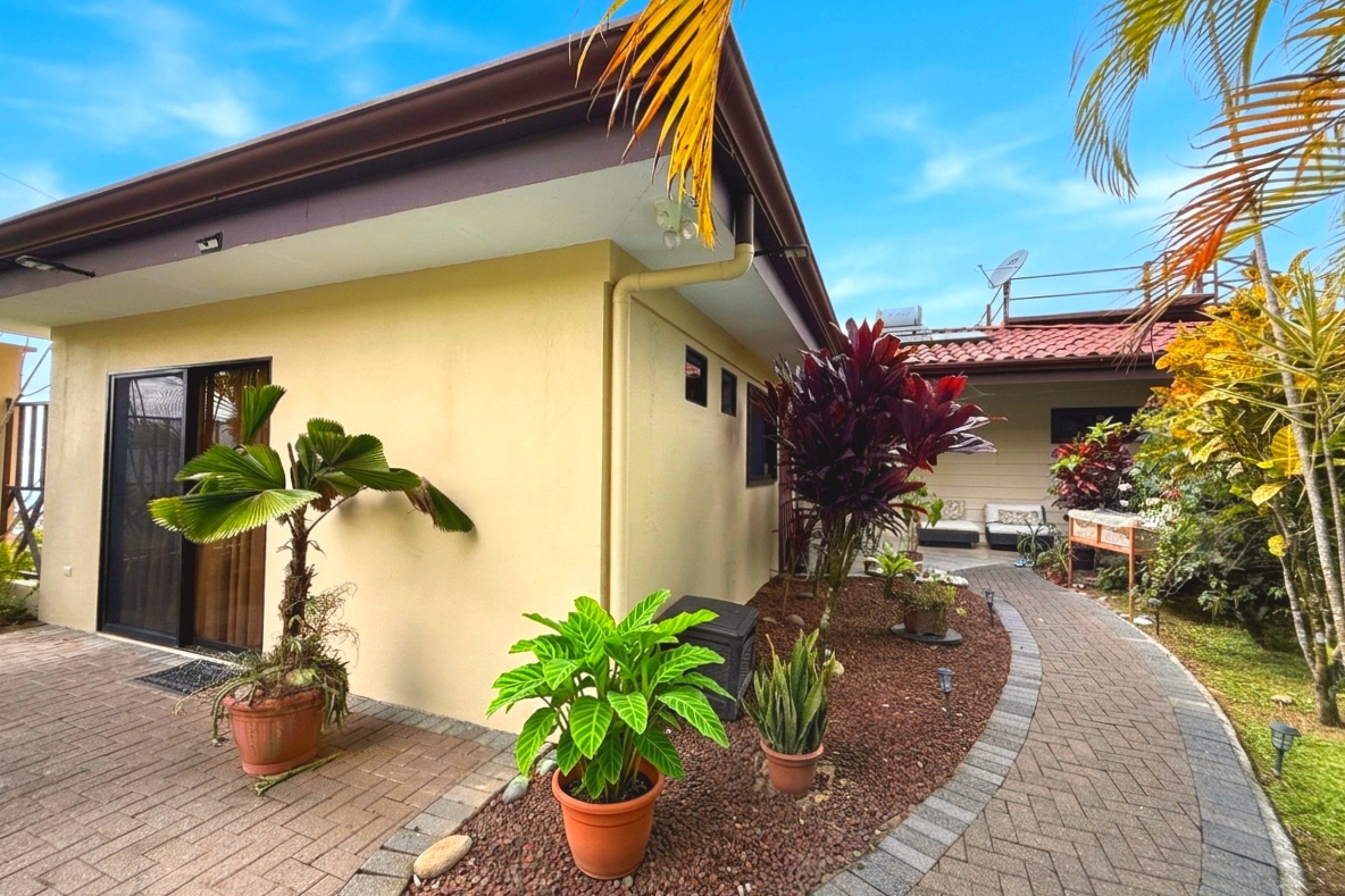 Tropical guesthouse exterior and paved garden pathway in Toucan Valley/Osa Mountain Village, Costa Rica.