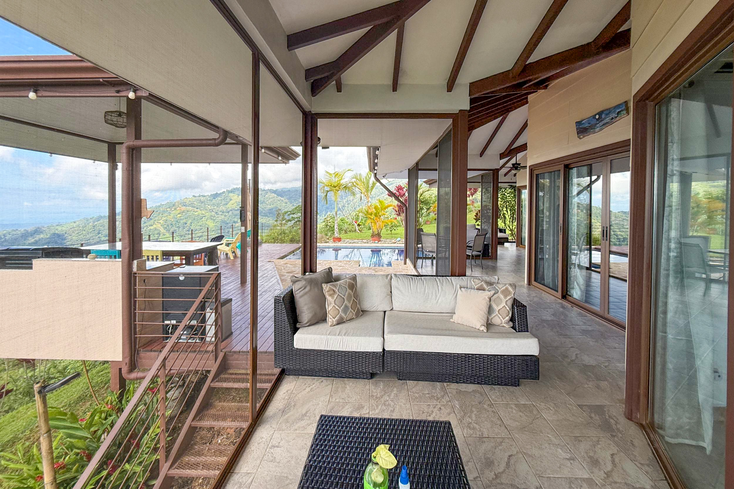 Covered patio with outdoor seating overlooking the pool and mountains in Toucan Valley, Costa Rica.
