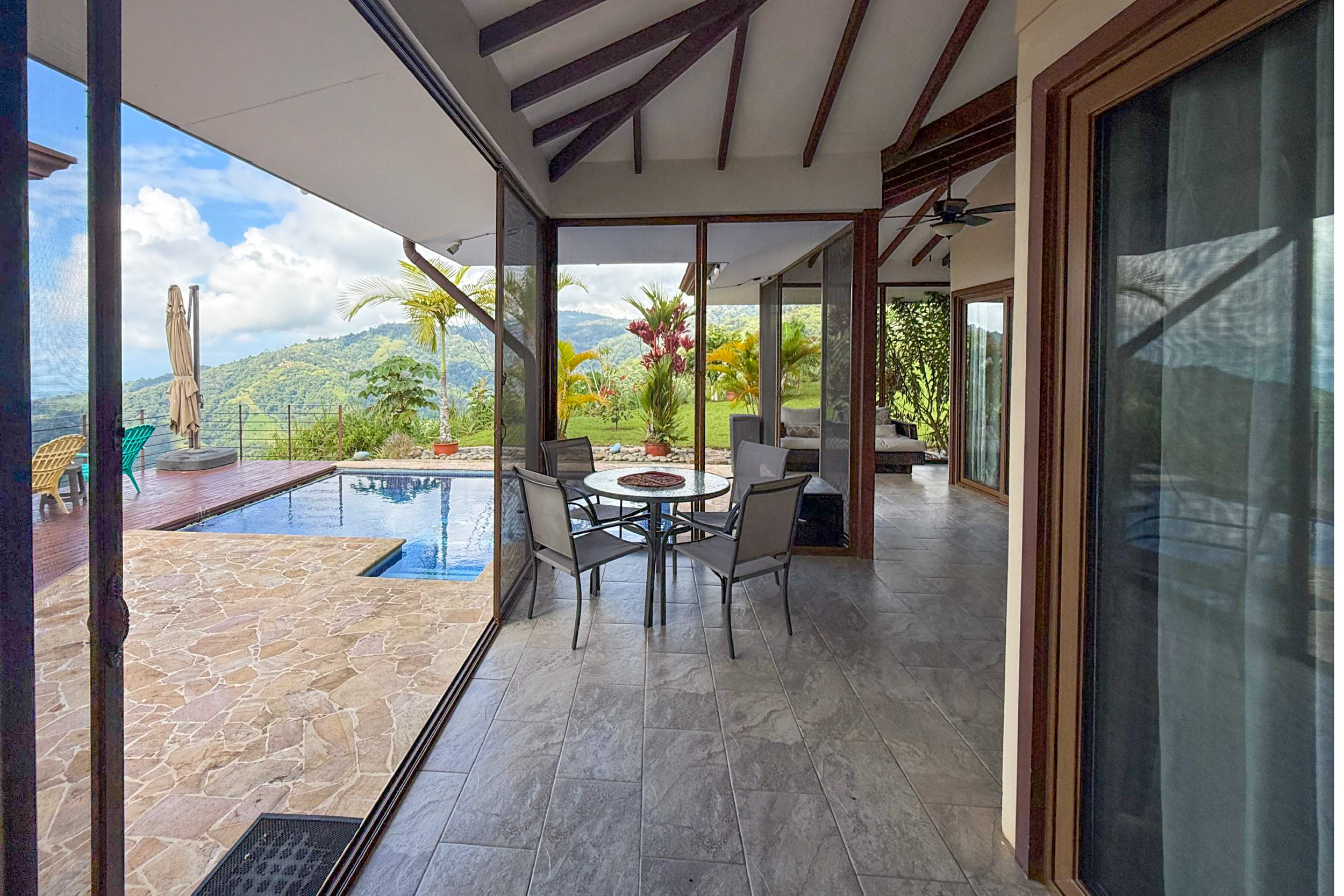 Covered terrace dining area opening to the pool and lush mountain views in Toucan Valley, Costa Rica.