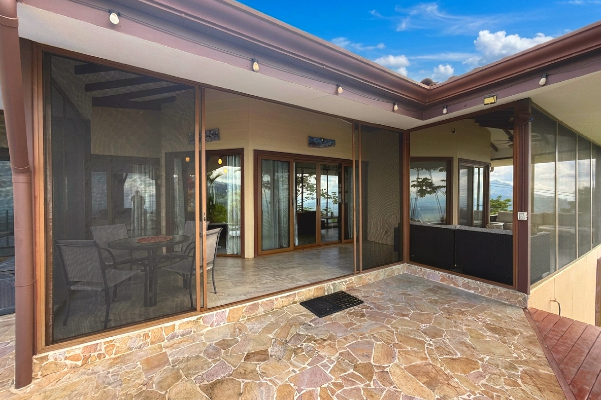 Covered flagstone patio with sliding screen doors and outdoor dining in Toucan Valley, Costa Rica.