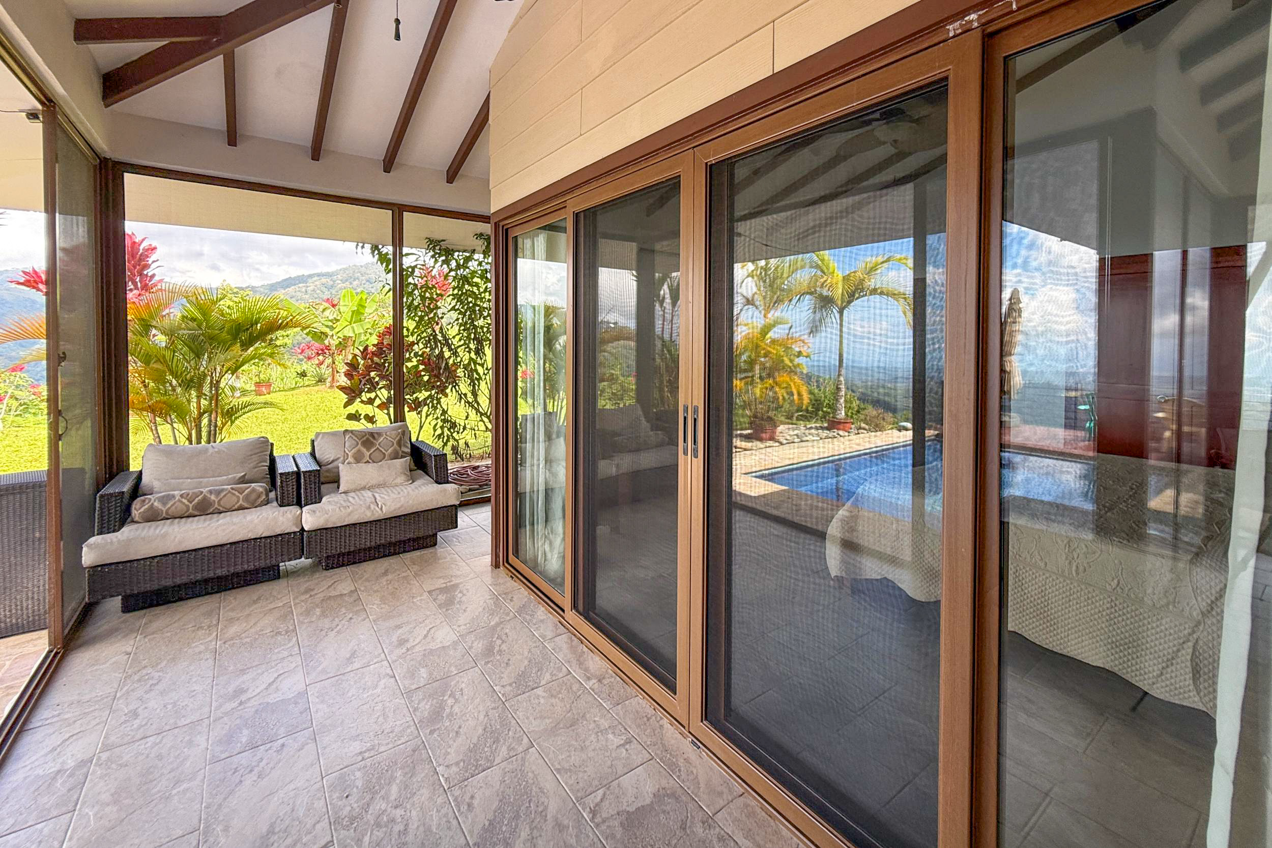 Tiled covered terrace with outdoor armchairs and large sliding doors in Toucan Valley, Costa Rica.