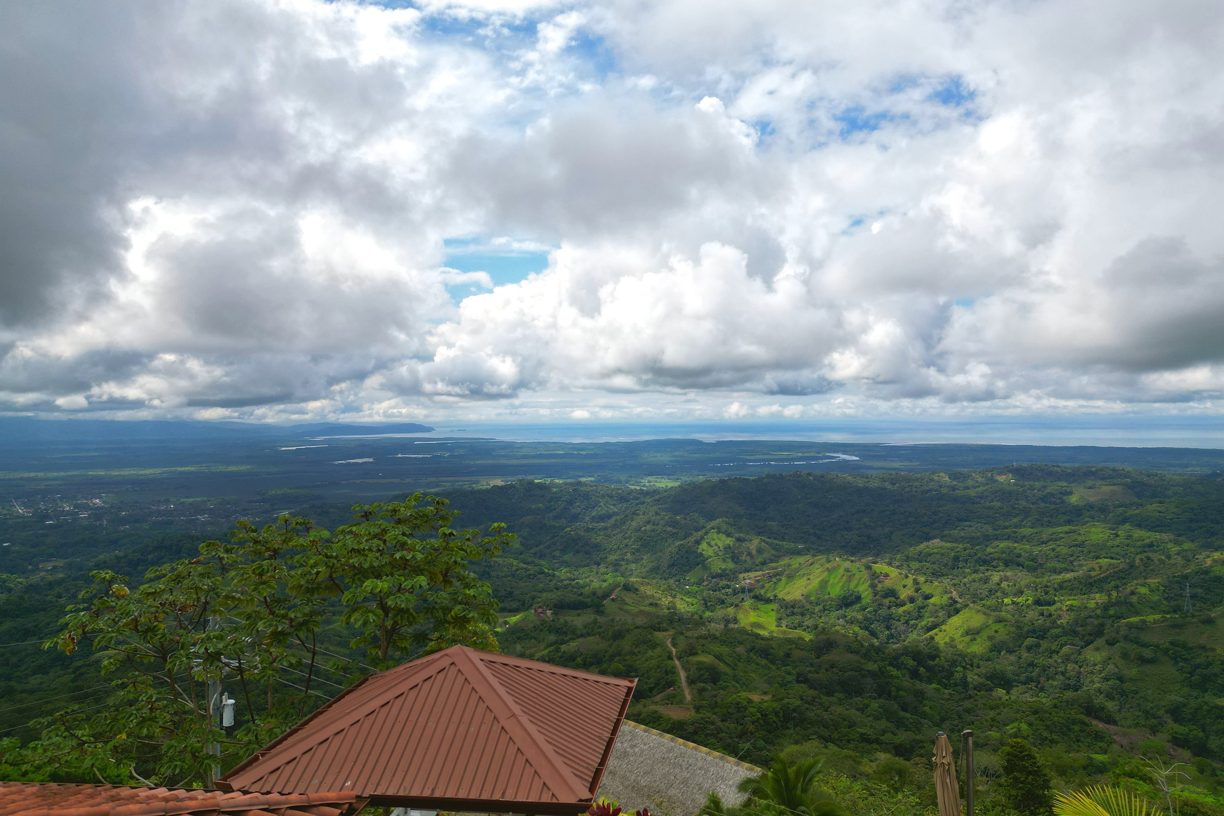Panoramic ocean and valley views over lush hills from a rooftop in Toucan Valley, Costa Rica.