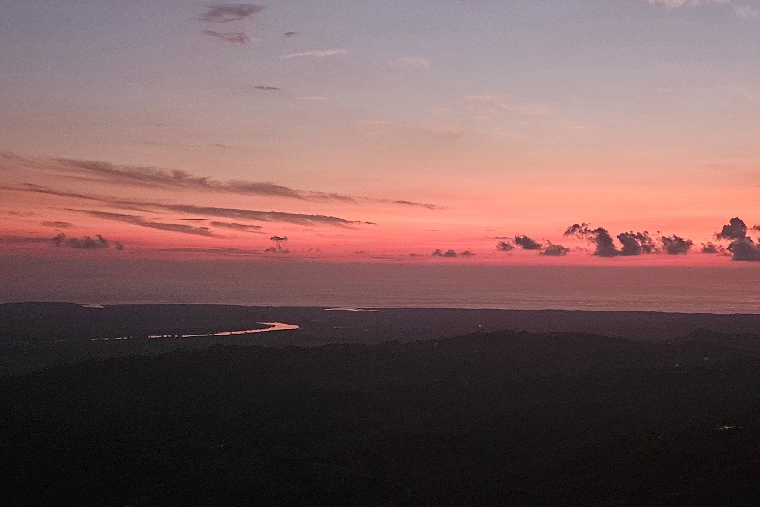 Sunset ocean view with a glowing river winding through the valley in Toucan Valley, Costa Rica.