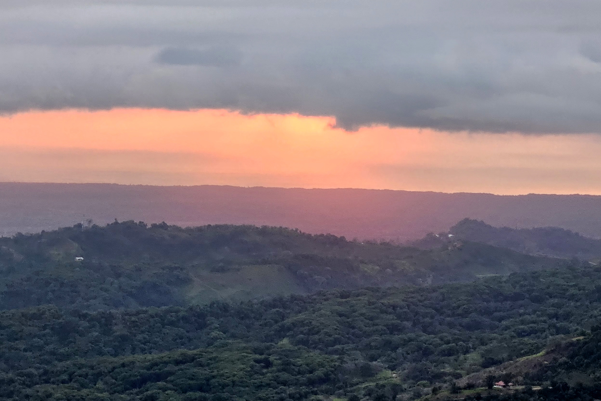 Golden sunset glowing over lush mountain ridges and the Osa Peninsula in Toucan Valley, Costa Rica.