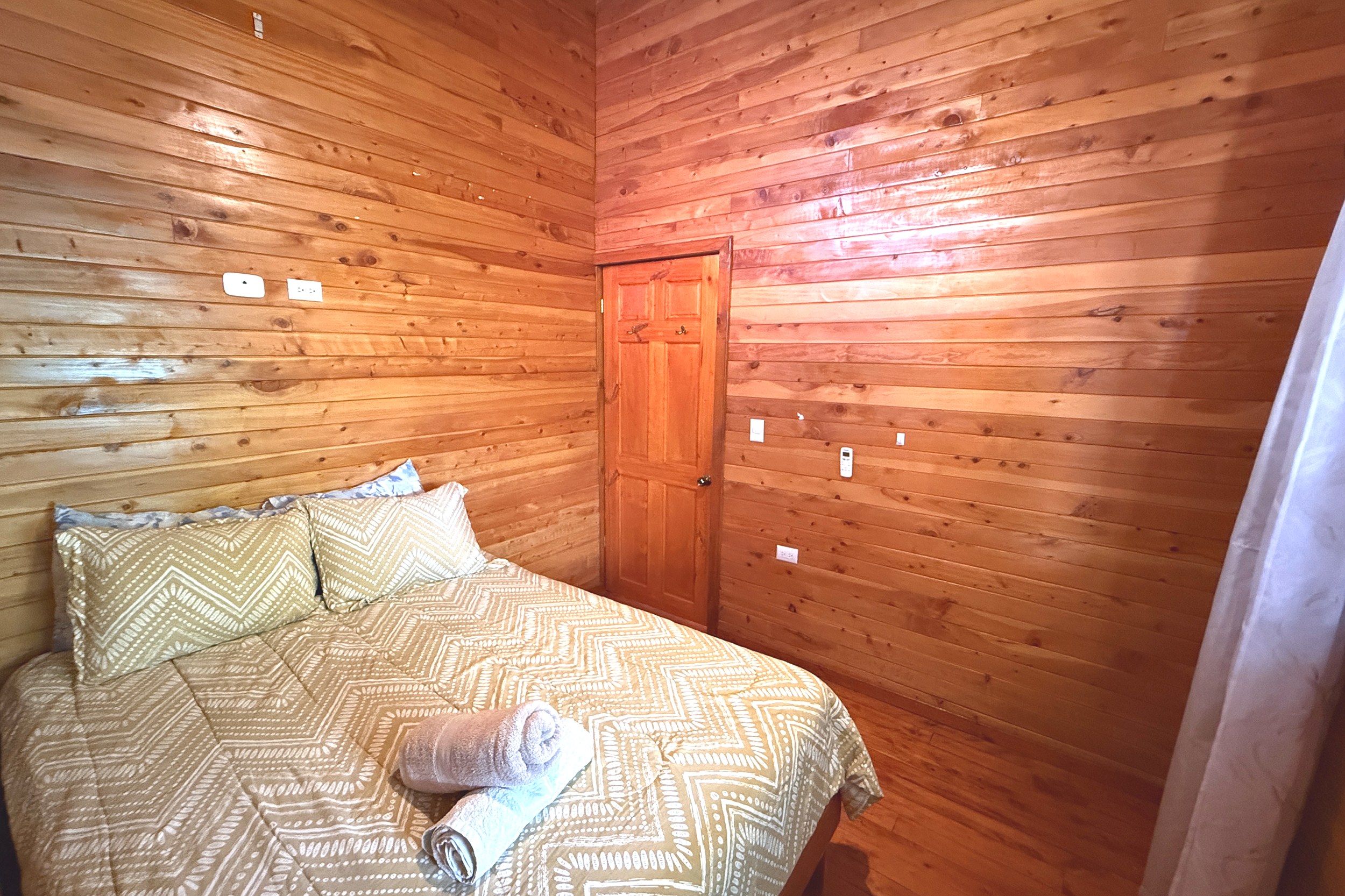 Cozy Cabin Bedroom Unique Income Producing Home wood cabin bedroom with bed in Bahia, Costa Rica.