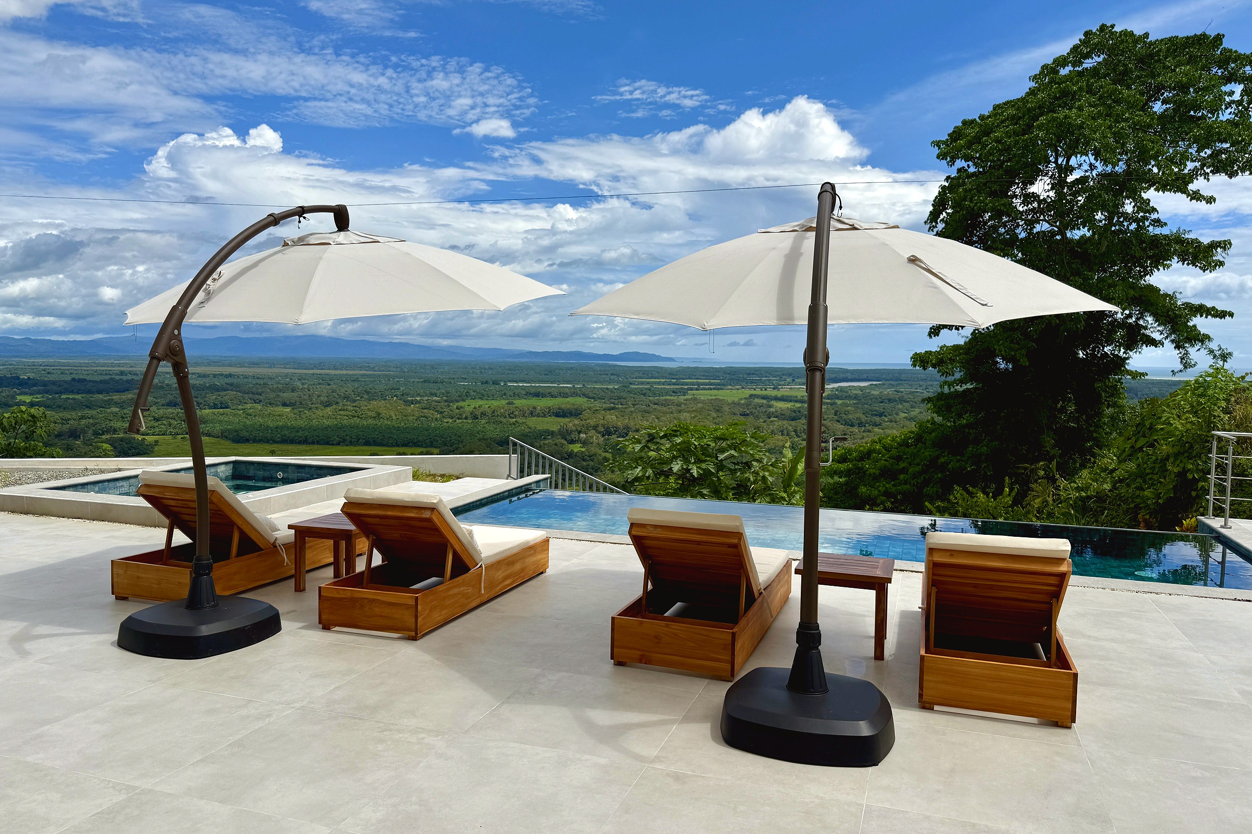 Luxury Hilltop Estate pool deck with lounge chairs and umbrellas in Costa Rica