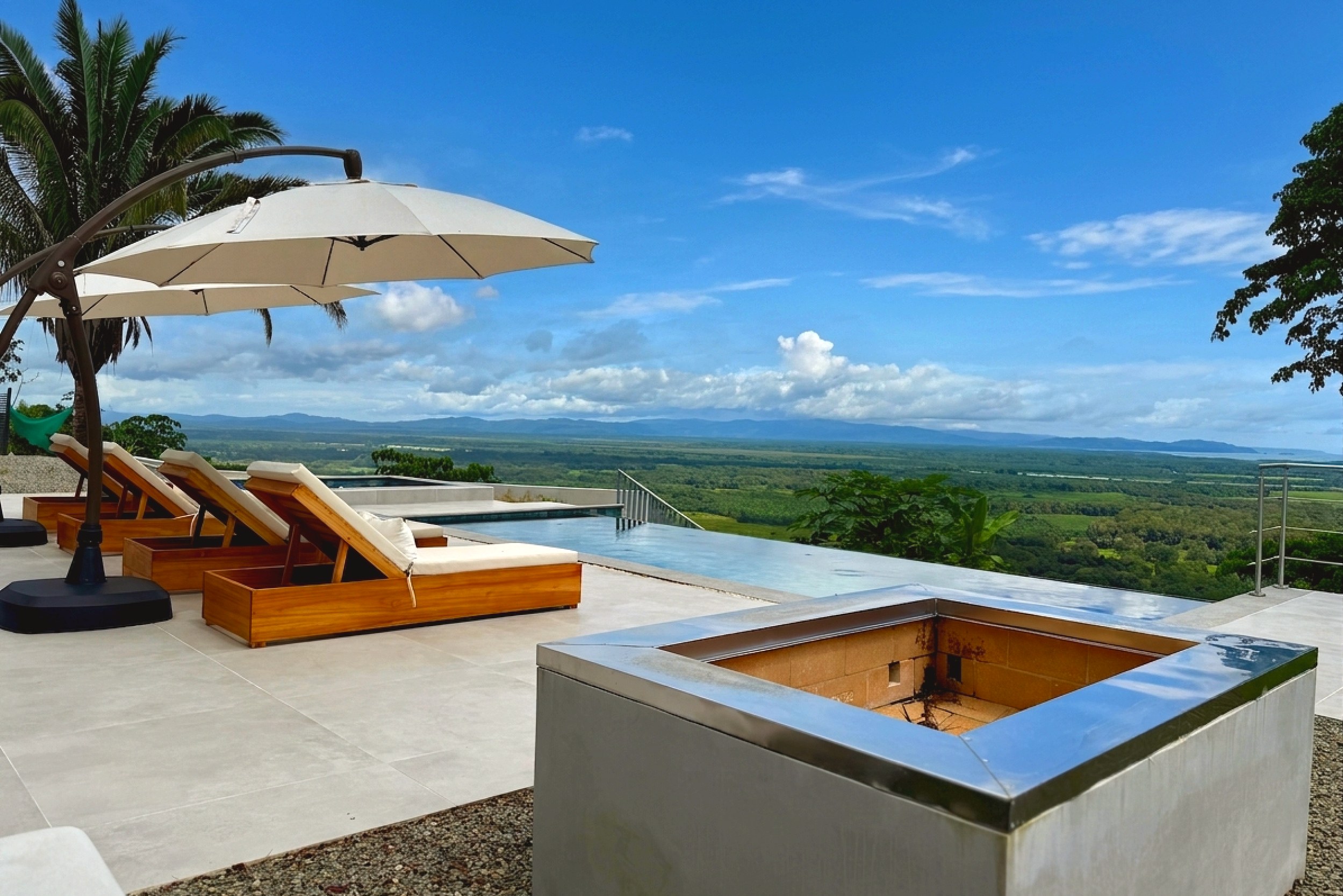 Modern Luxury Villa infinity pool, lounge chairs, and fire pit with expansive jungle views in Costa Rica.