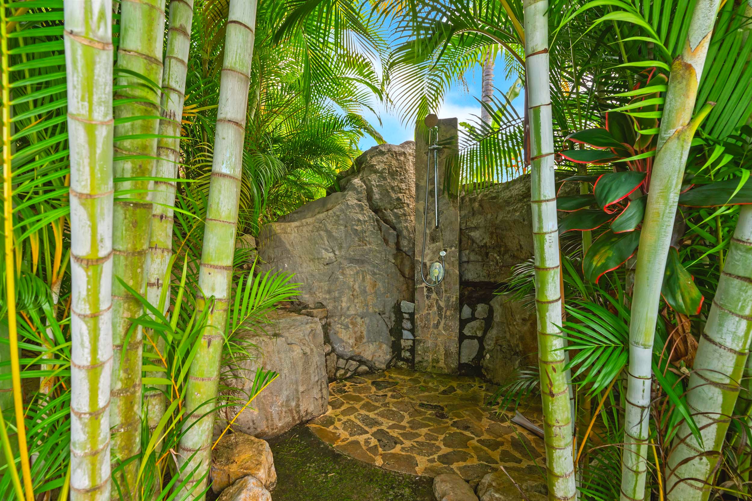Luxurious Home outdoor stone shower amidst palm trees in Chontales, Costa Rica