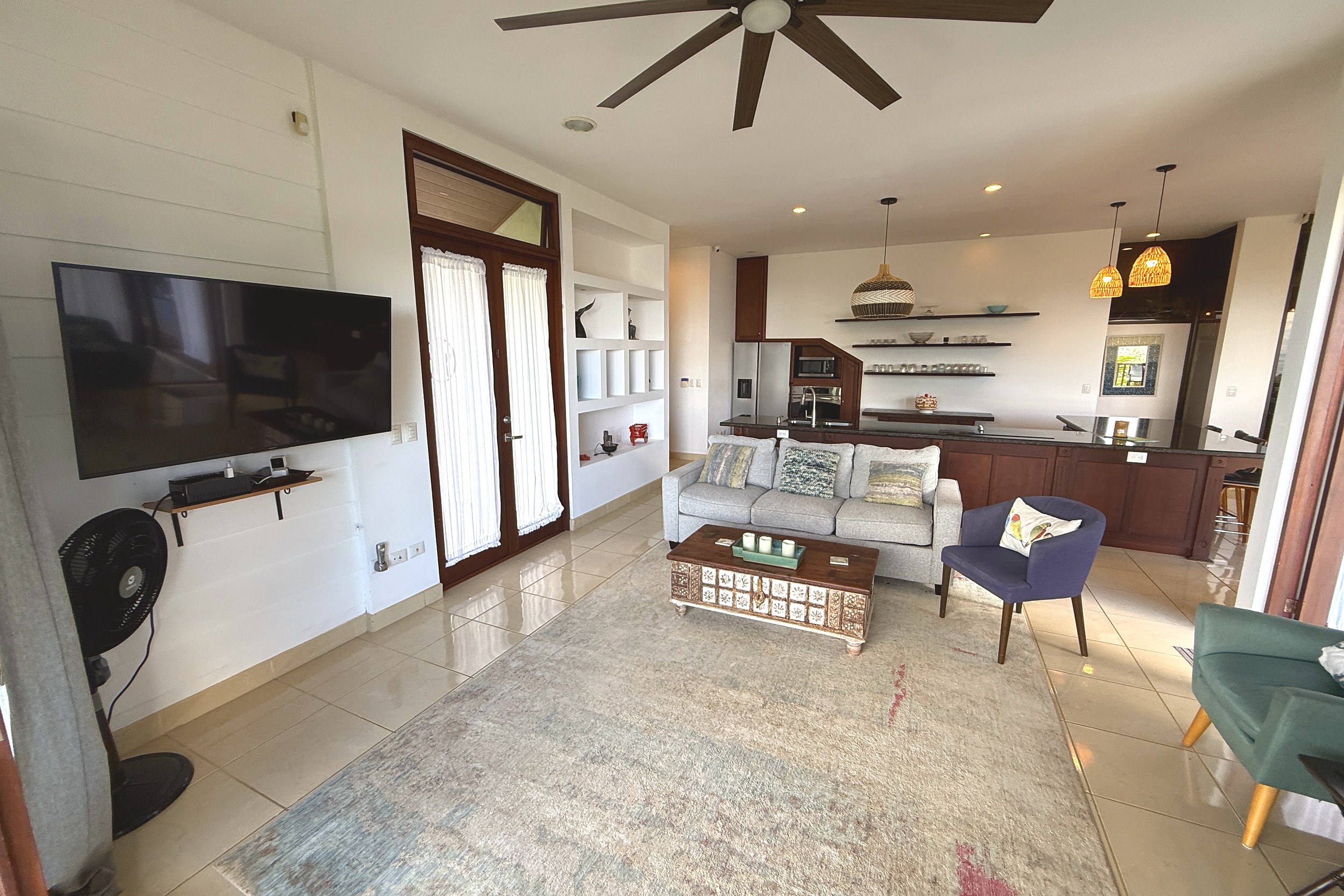 Open-Concept Living Room Panoramic Ocean View Home living room with sofa, TV, and open kitchen in Ojochal, Costa Rica.