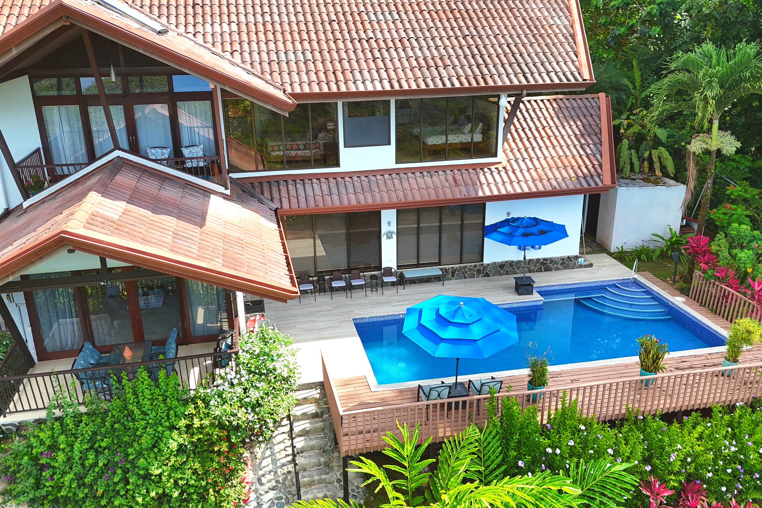 Pool Deck & Terrace Ocean View Home pool deck with blue umbrellas and tiled roof in Ojochal, Costa Rica
