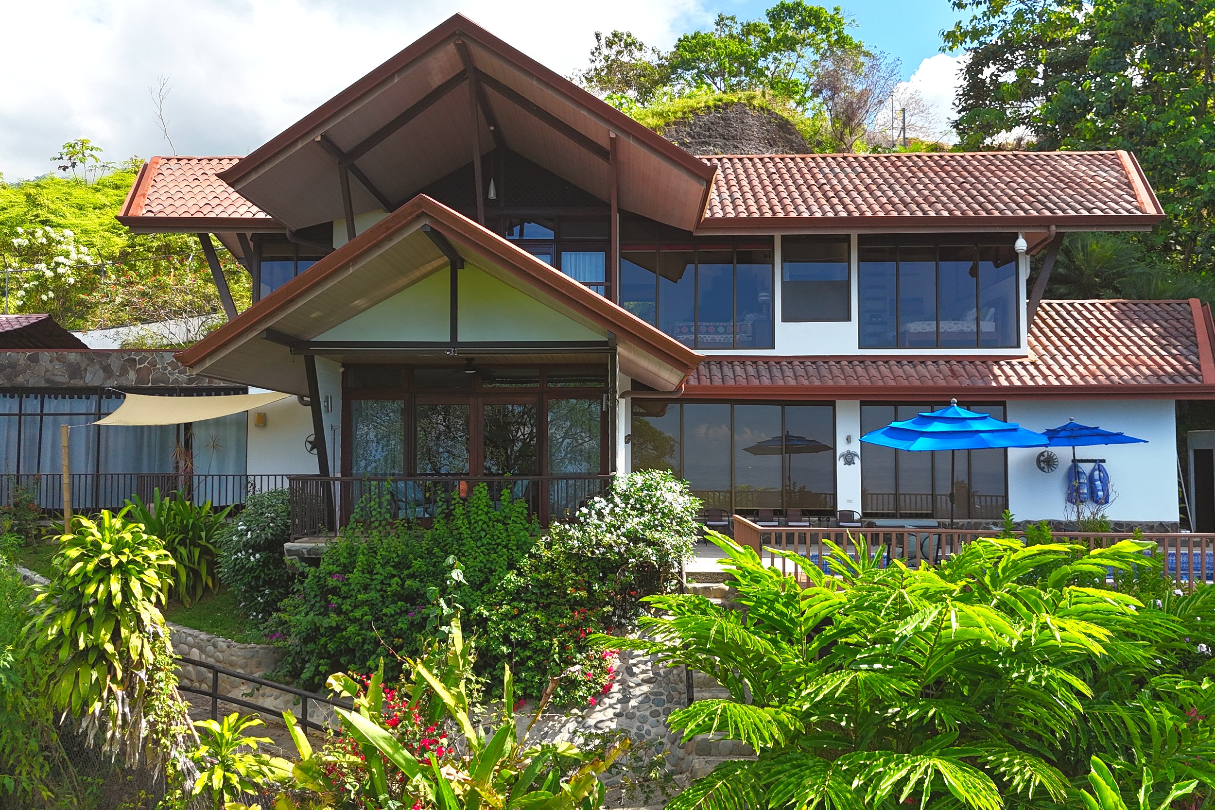 Tropical Front Exterior View Ocean View Home with tropical gardens and blue umbrellas in Ojochal, Costa Rica