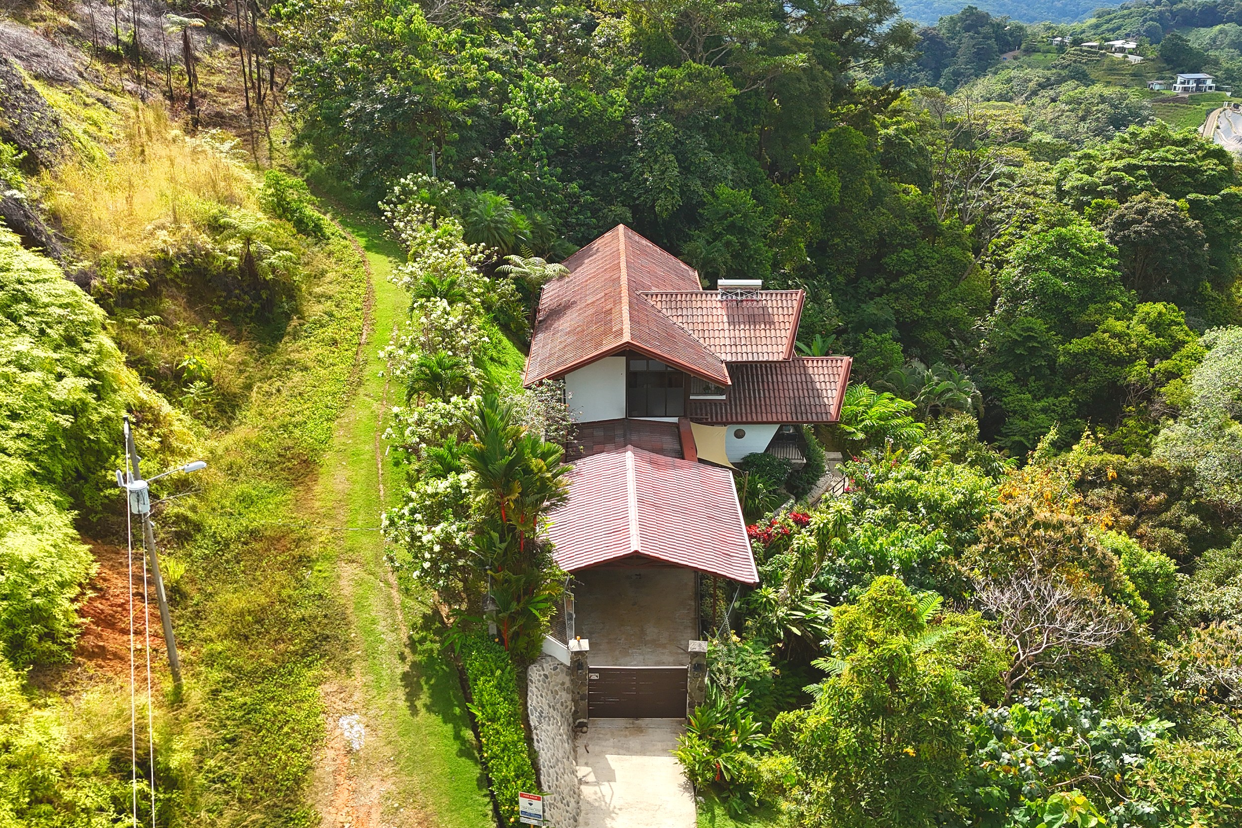 Aerial Hillside Home View Panoramic Ocean View Home aerial view of tiered red-roof house amid lush hillside in Ojochal, Costa Rica