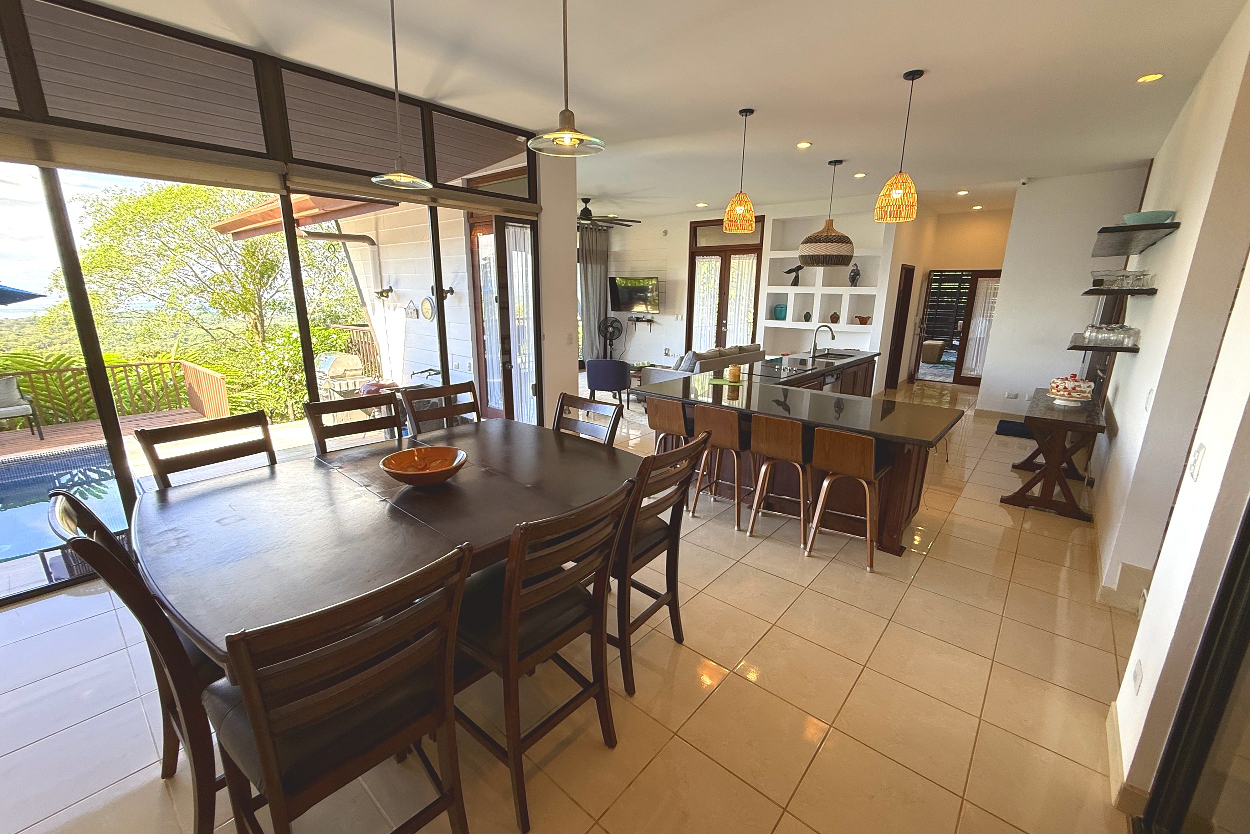 Open-Concept Dining & Kitchen Panoramic Ocean View Home dining area with kitchen island and pool view in Ojochal, Costa Rica