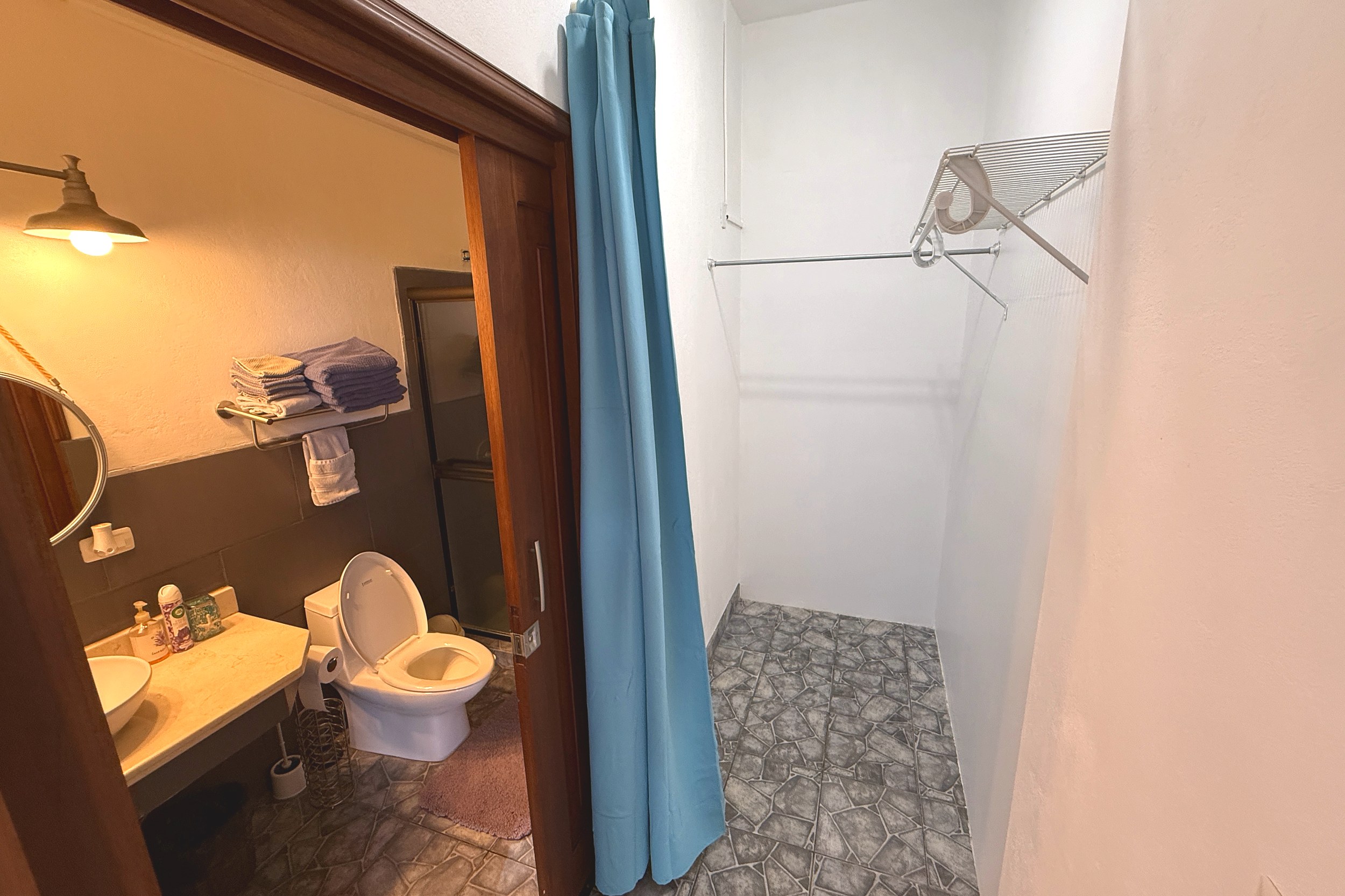 Downstairs Guest Bathroom & Shower Ocean View Home walk-in shower with blue curtain and toilet area in Ojochal, Costa Rica