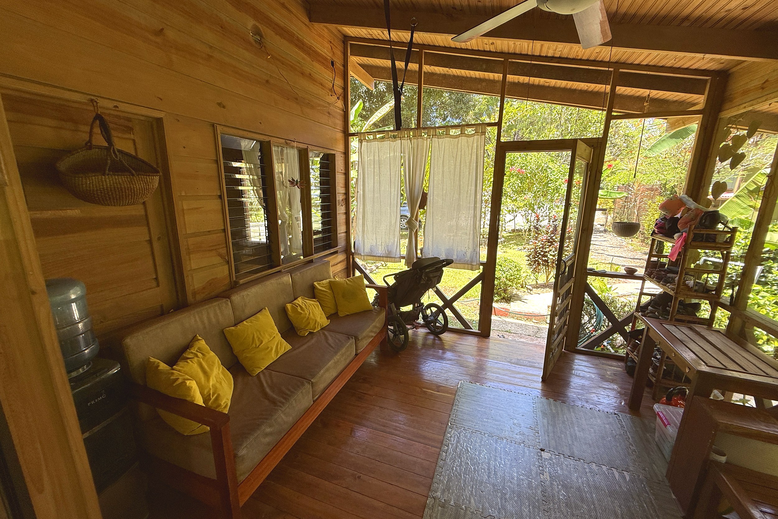 Cozy Wooden Living Room Jungle Hotel wooden living room with yellow-cushioned sofa opening to porch in Ojochal, Costa Rica