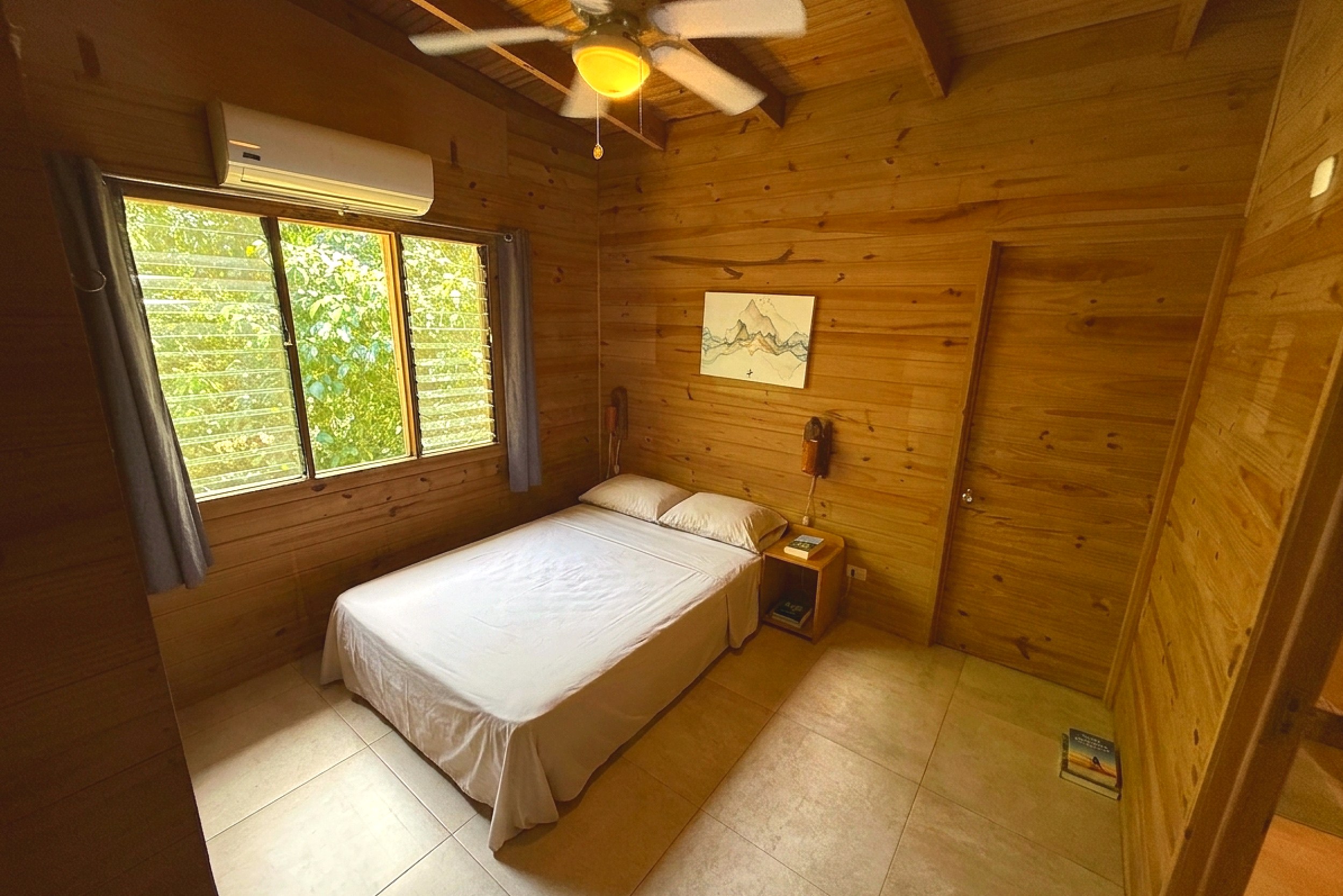 Wood-Paneled Guest Bedroom Jungle Hotel wood-paneled bedroom with double bed and jungle view window in Ojochal, Costa Rica