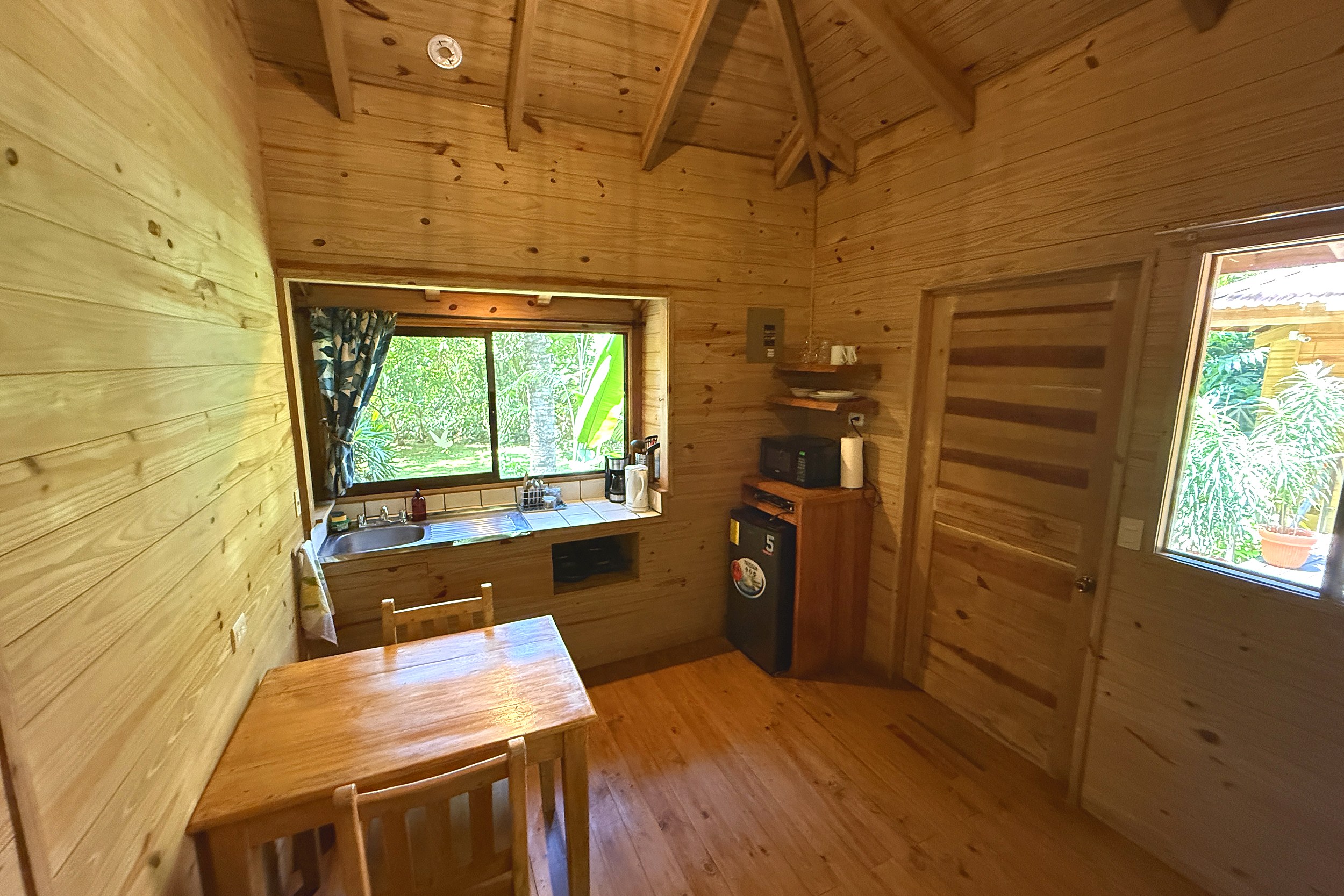 Wooden Guesthouse Dining Nook Jungle Hotel wooden guesthouse kitchenette with dining table and window view in Ojochal, Costa Rica
