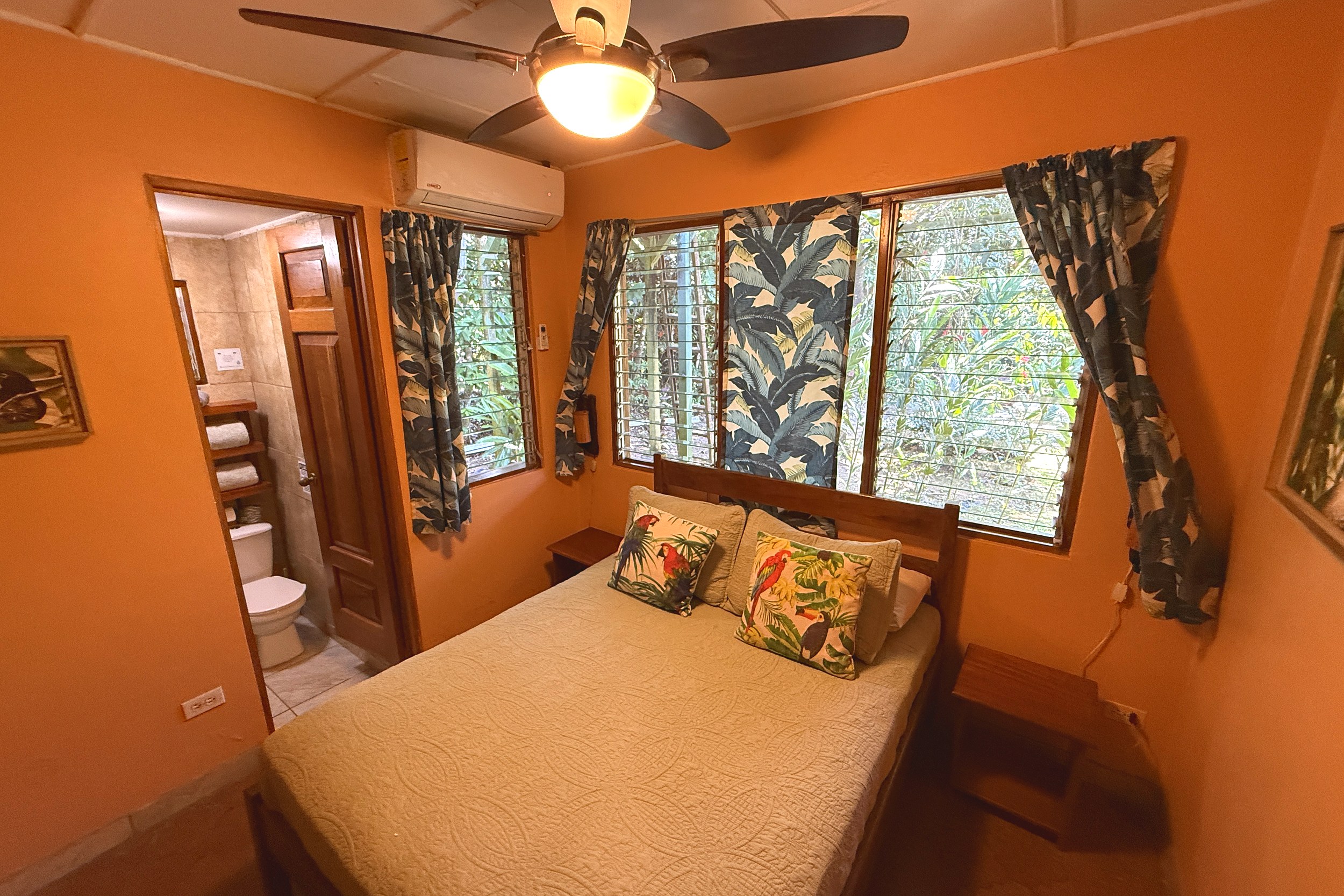 Guesthouse Master Bedroom Jungle Hotel guesthouse bedroom with tropical decor, ceiling fan and jungle-view windows in Ojochal, Costa Rica