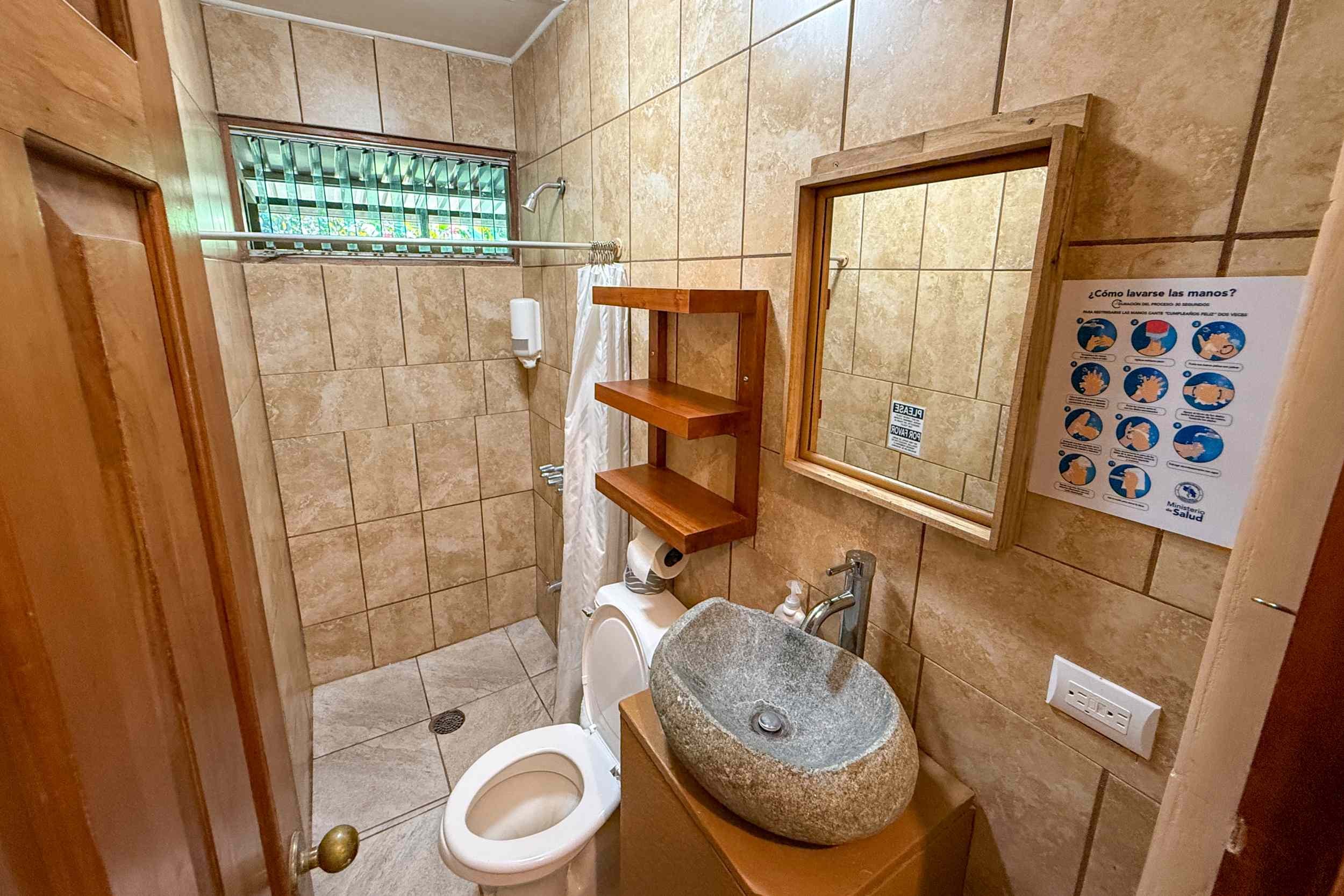 Guest Bathroom with Stone Sink Jungle Hotel guest bathroom with stone vessel sink and tiled shower in Ojochal, Costa Rica