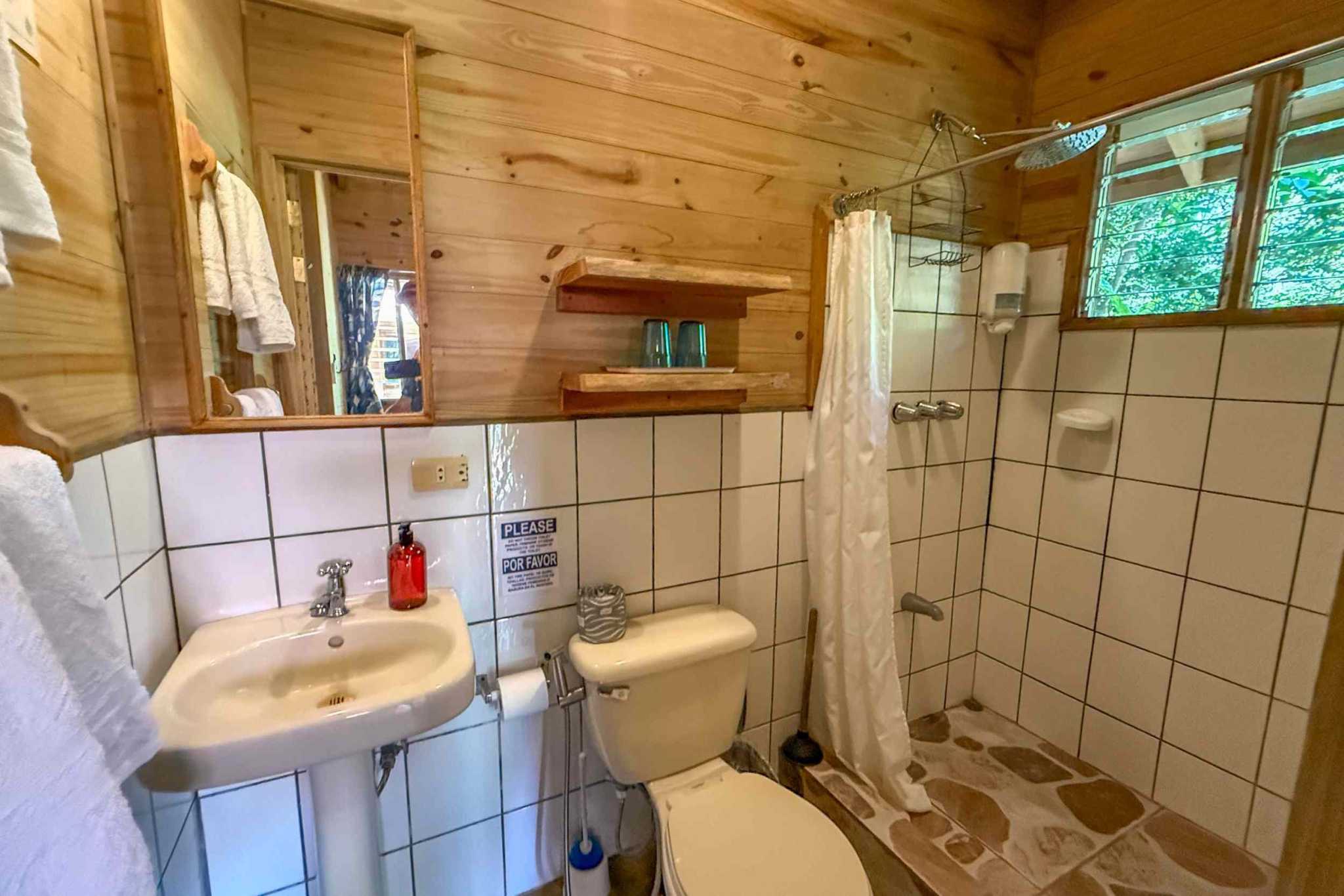 Jungle Hotel wood-paneled guest bathroom with tiled shower in Ojochal, Costa Rica