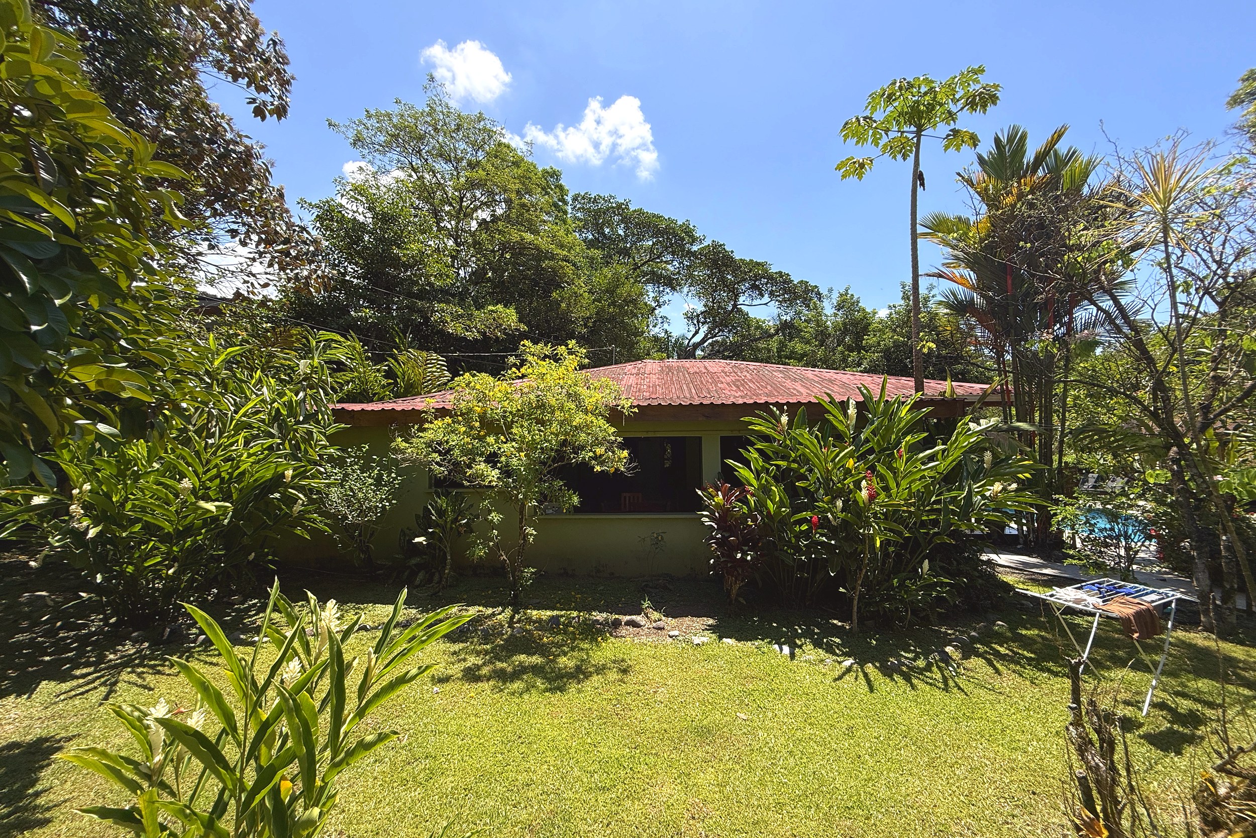 Back Exterior & Pool View Jungle Hotel back exterior with tin roof, lush garden and pool in Ojochal, Costa Rica