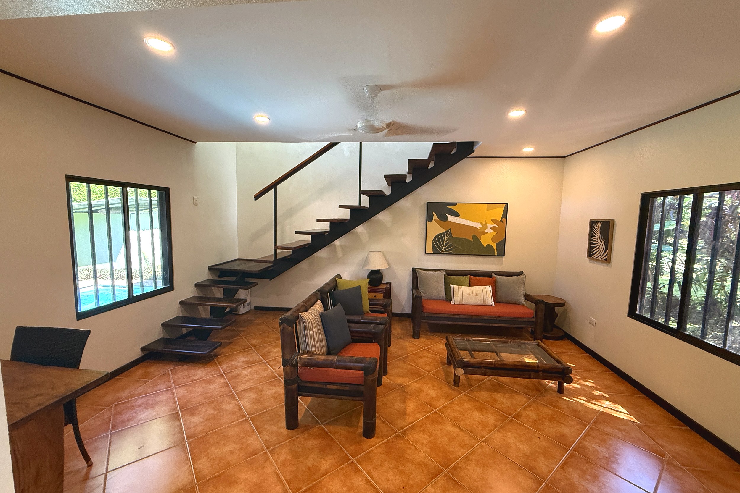 Living Room & Staircase Jungle Sanctuary living room with wood staircase, tropical decor, and pool view in Ojochal, Costa Rica.