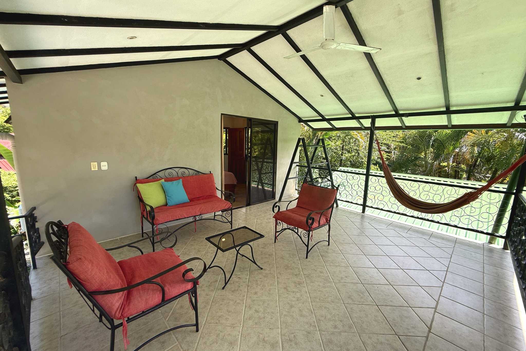Balcony Lounge & Hammock Jungle Sanctuary covered balcony with red cushioned seating and hammock in Ojochal, Costa Rica